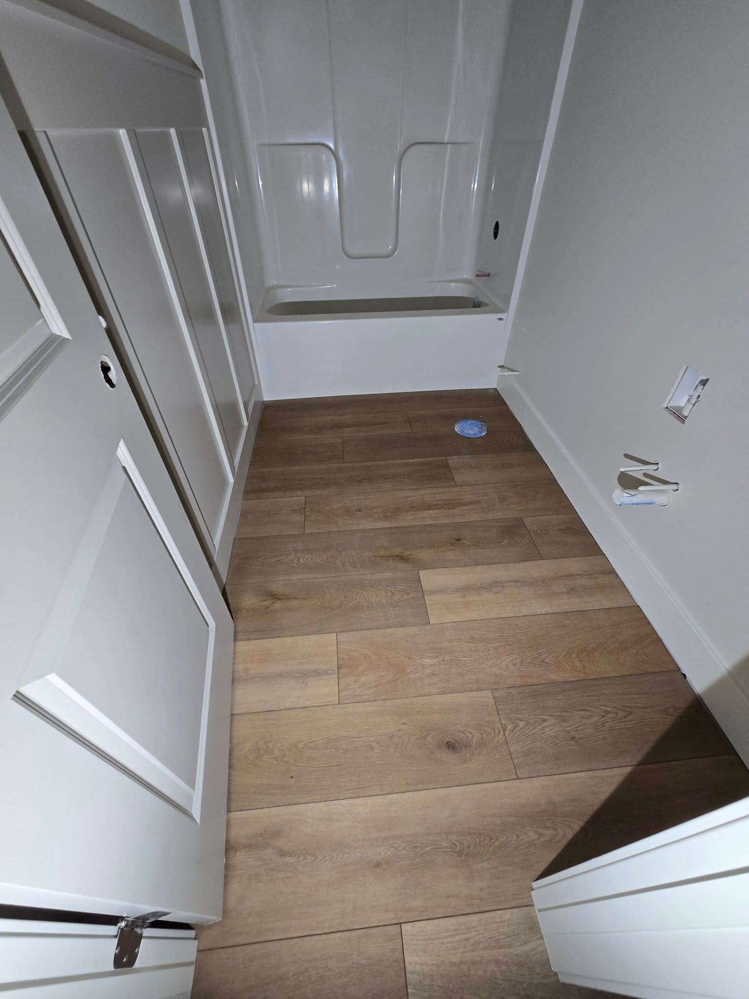 A bathroom with a bathtub and a wooden floor