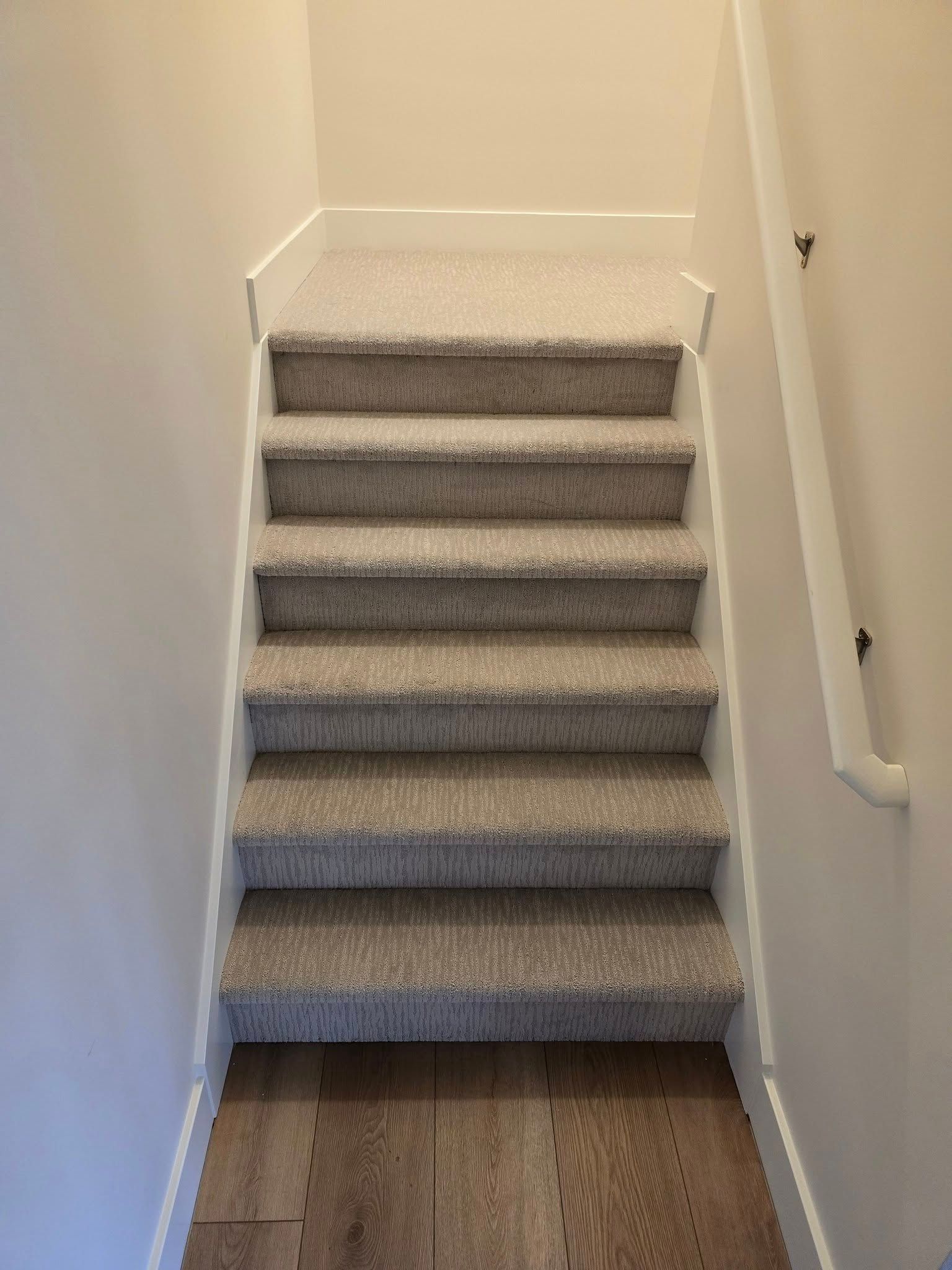 A set of stairs with carpeted steps and a wooden floor.