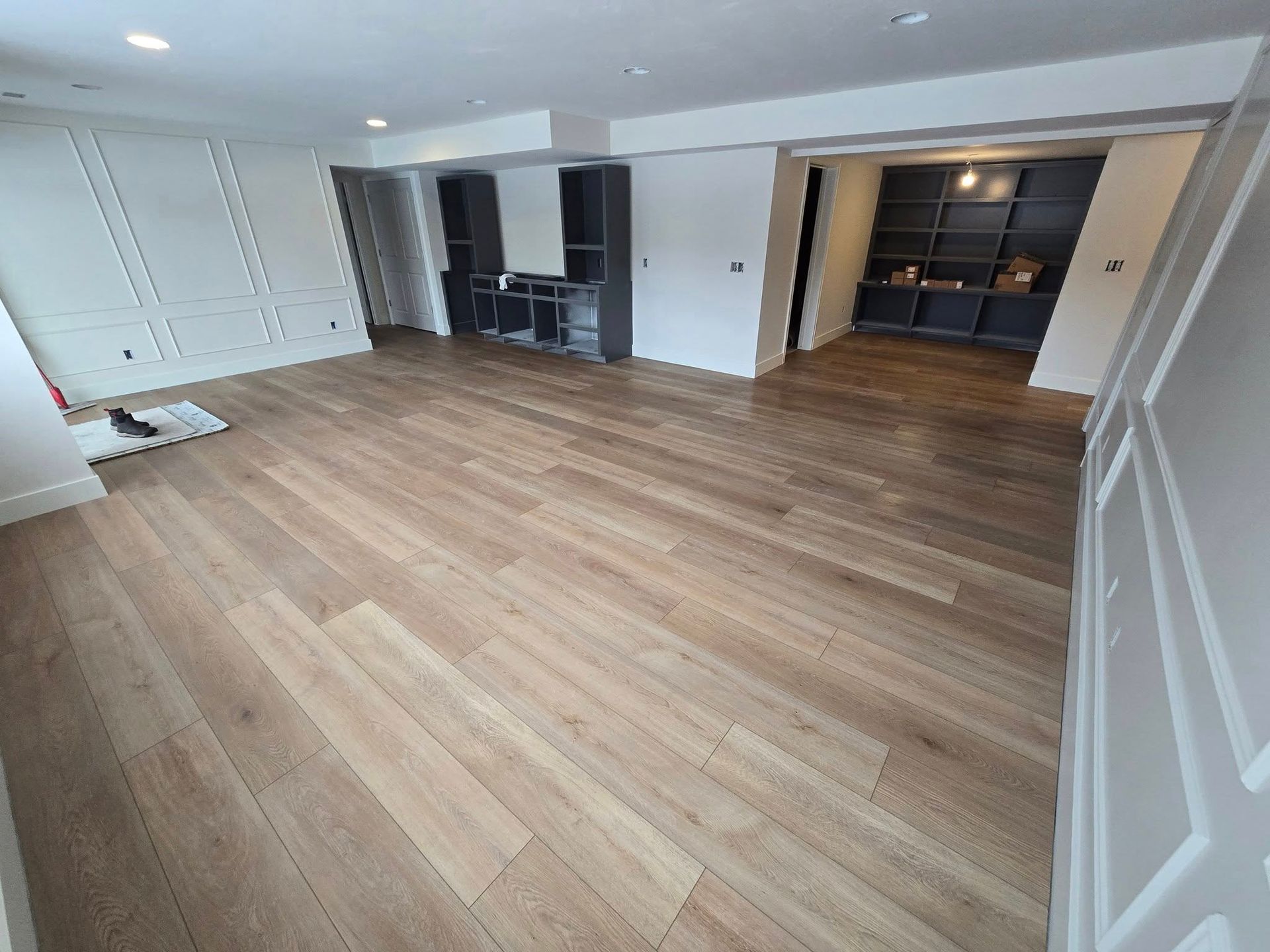 A large empty room with hardwood floors and white walls.