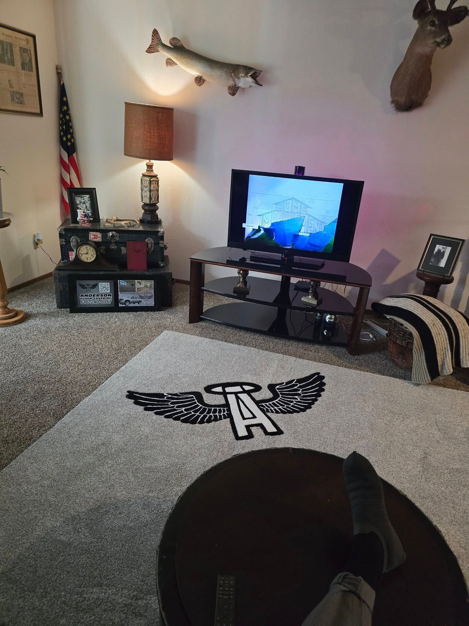 A living room with a flat screen tv and a rug with the letter a on it.