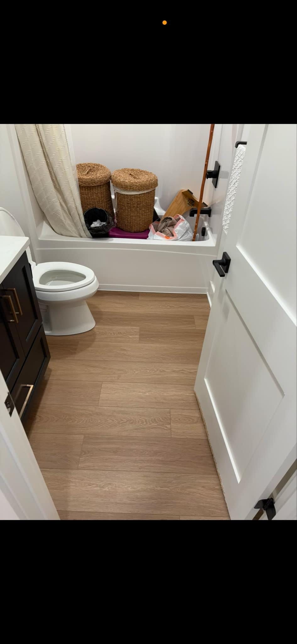 A bathroom with a toilet , sink , bathtub and laundry baskets.