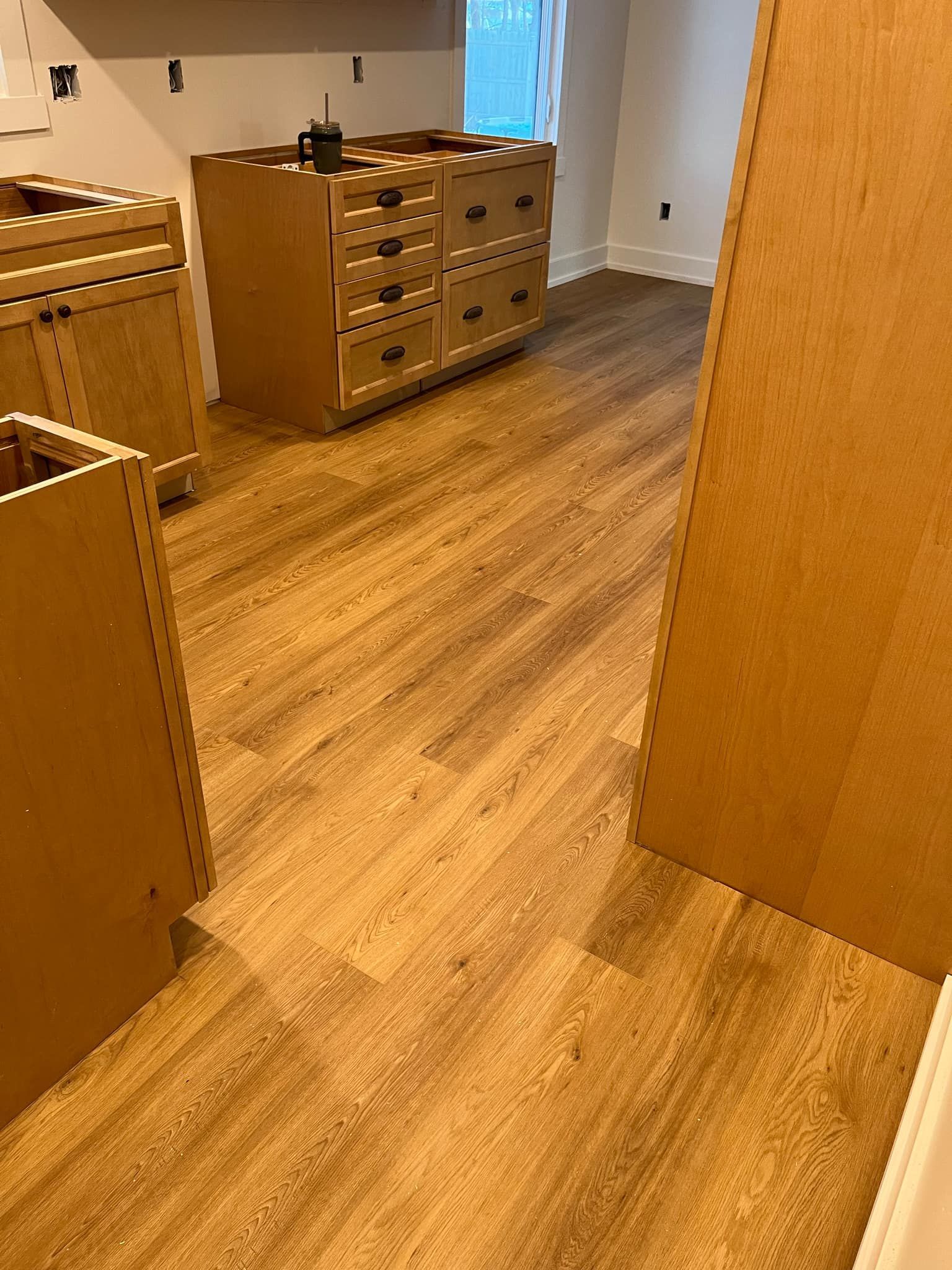 A kitchen with wooden floors and cabinets under construction.