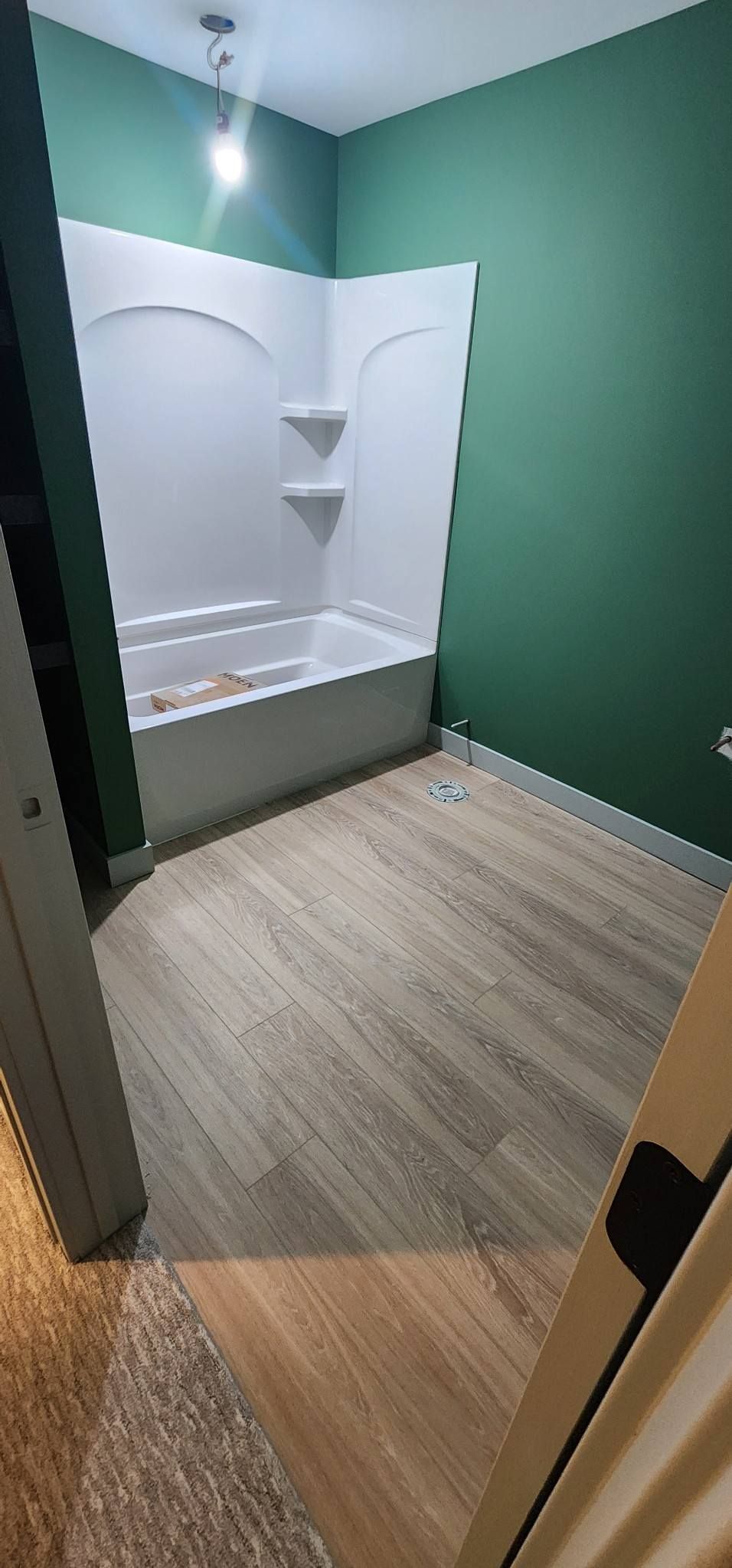 A bathroom with a bathtub and green walls.