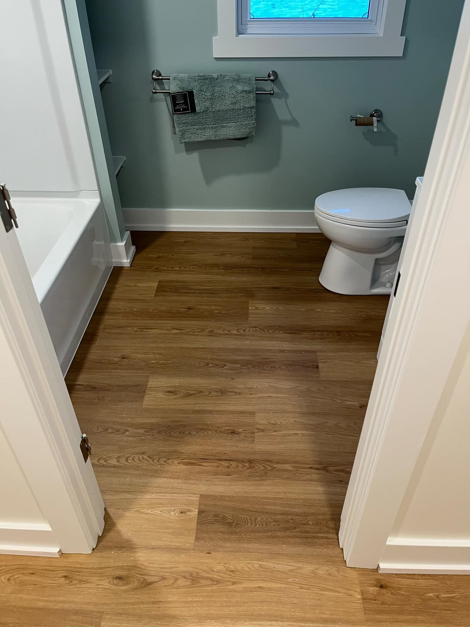 A bathroom with a toilet , tub , and window.