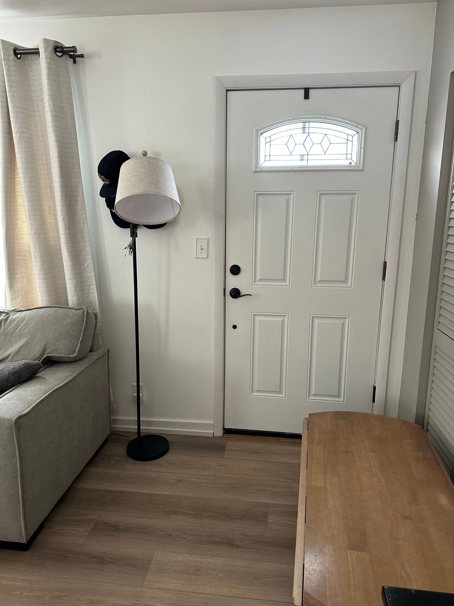 A living room with a couch , lamp , and door.