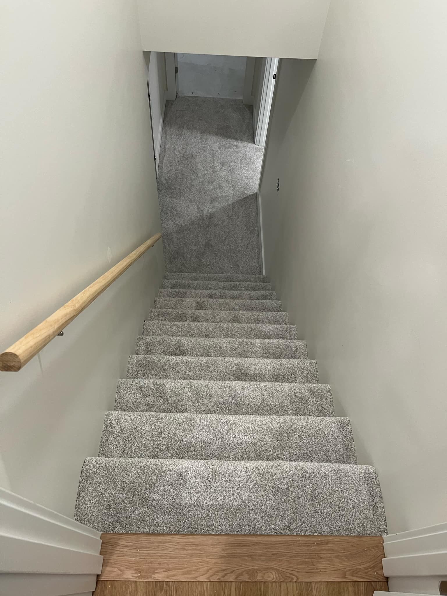 A set of stairs leading up to a basement with a wooden railing.