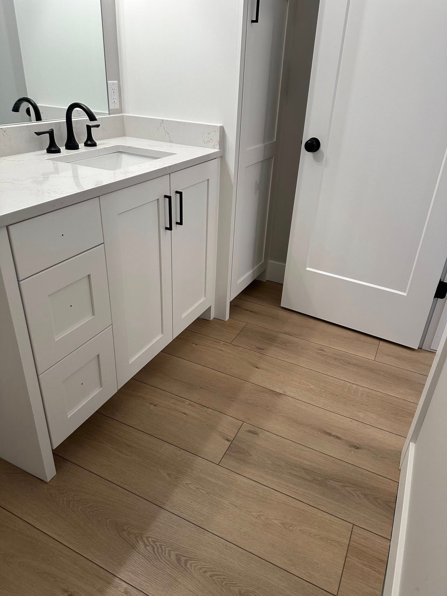 A bathroom with a sink , mirror and hardwood floor.
