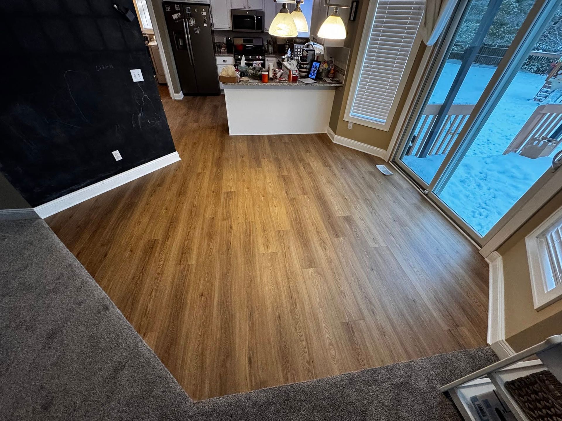 A kitchen with a wooden floor and sliding glass doors.