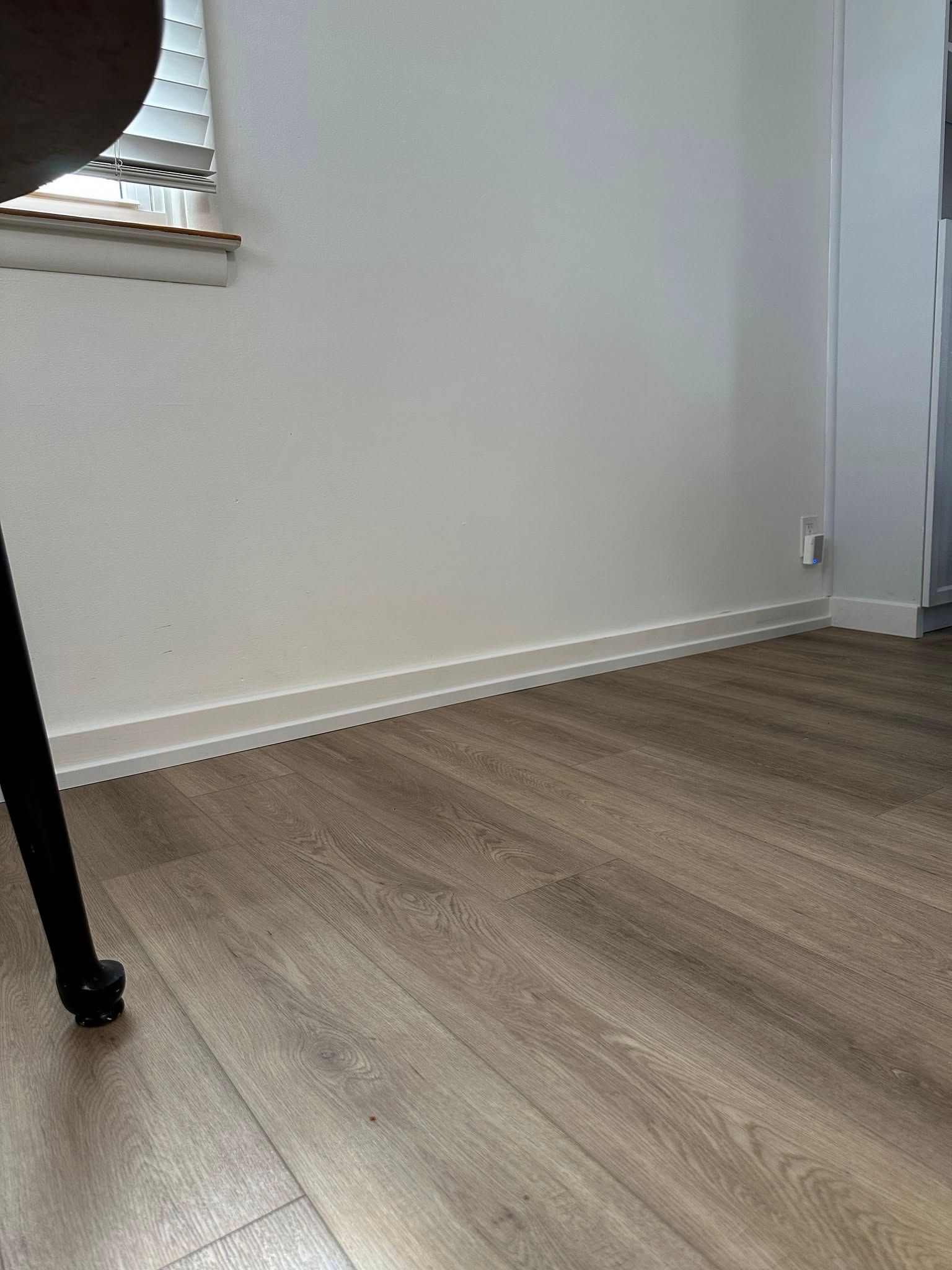 A room with a wooden floor , white walls and a window.