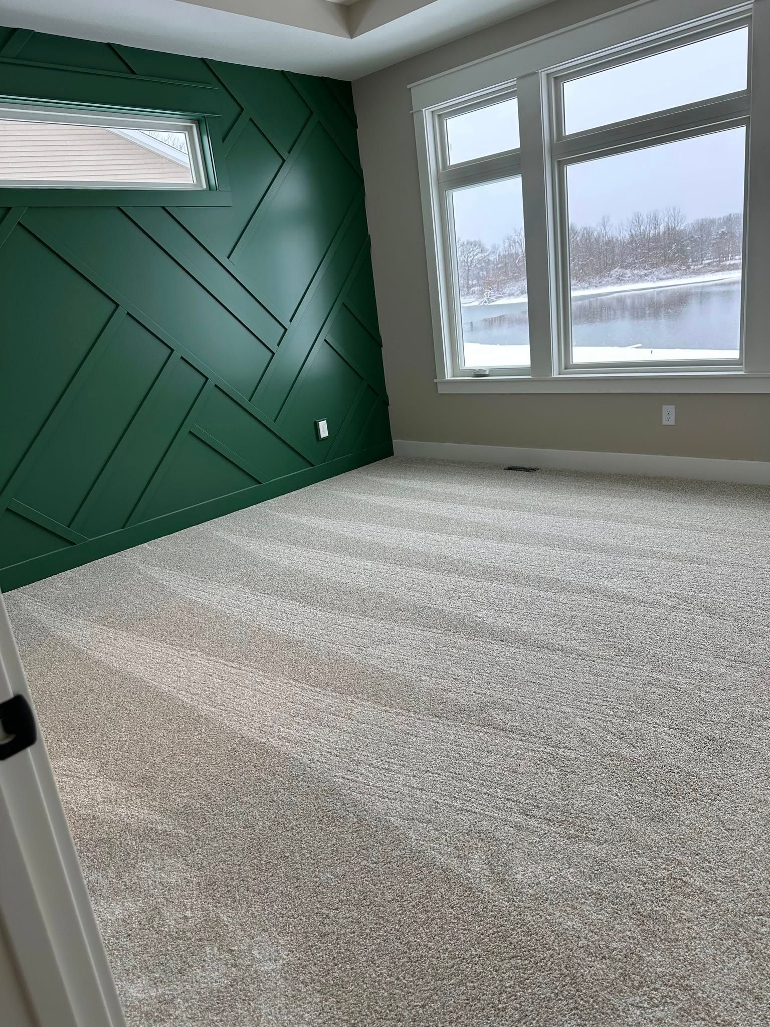 An empty room with a green wall and a white carpet.