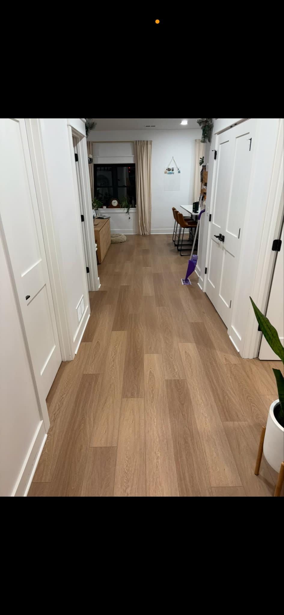 A long hallway with hardwood floors and white walls.