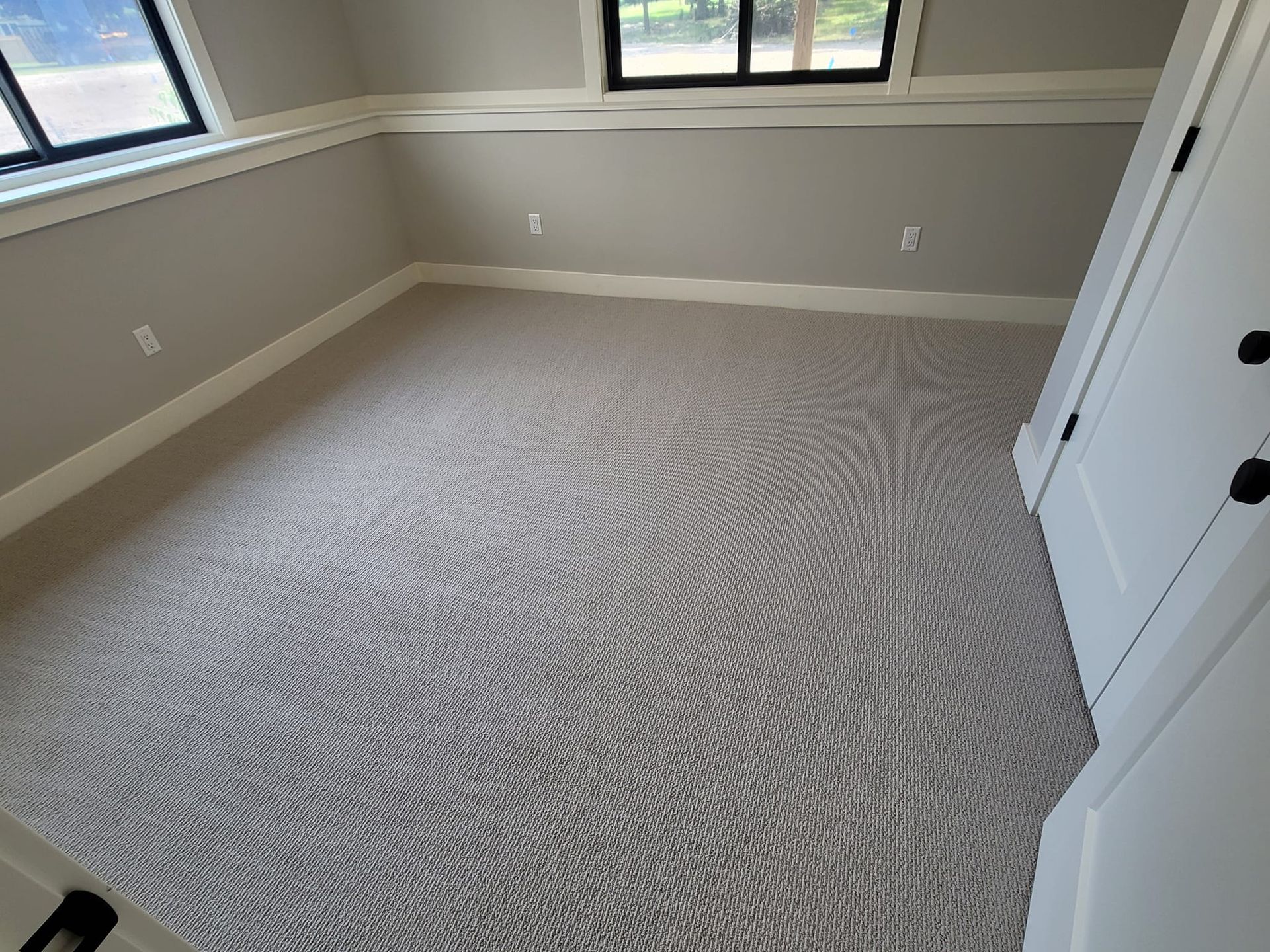 A bedroom with a large carpeted floor and a window.