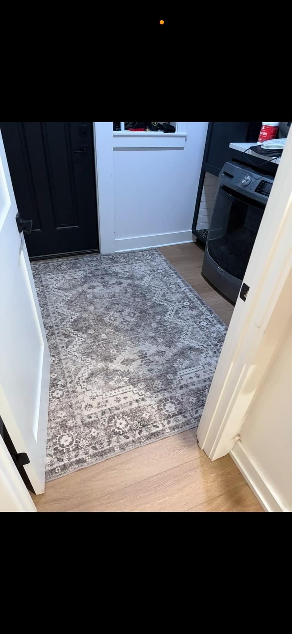 A kitchen with a rug on the floor and a door open.