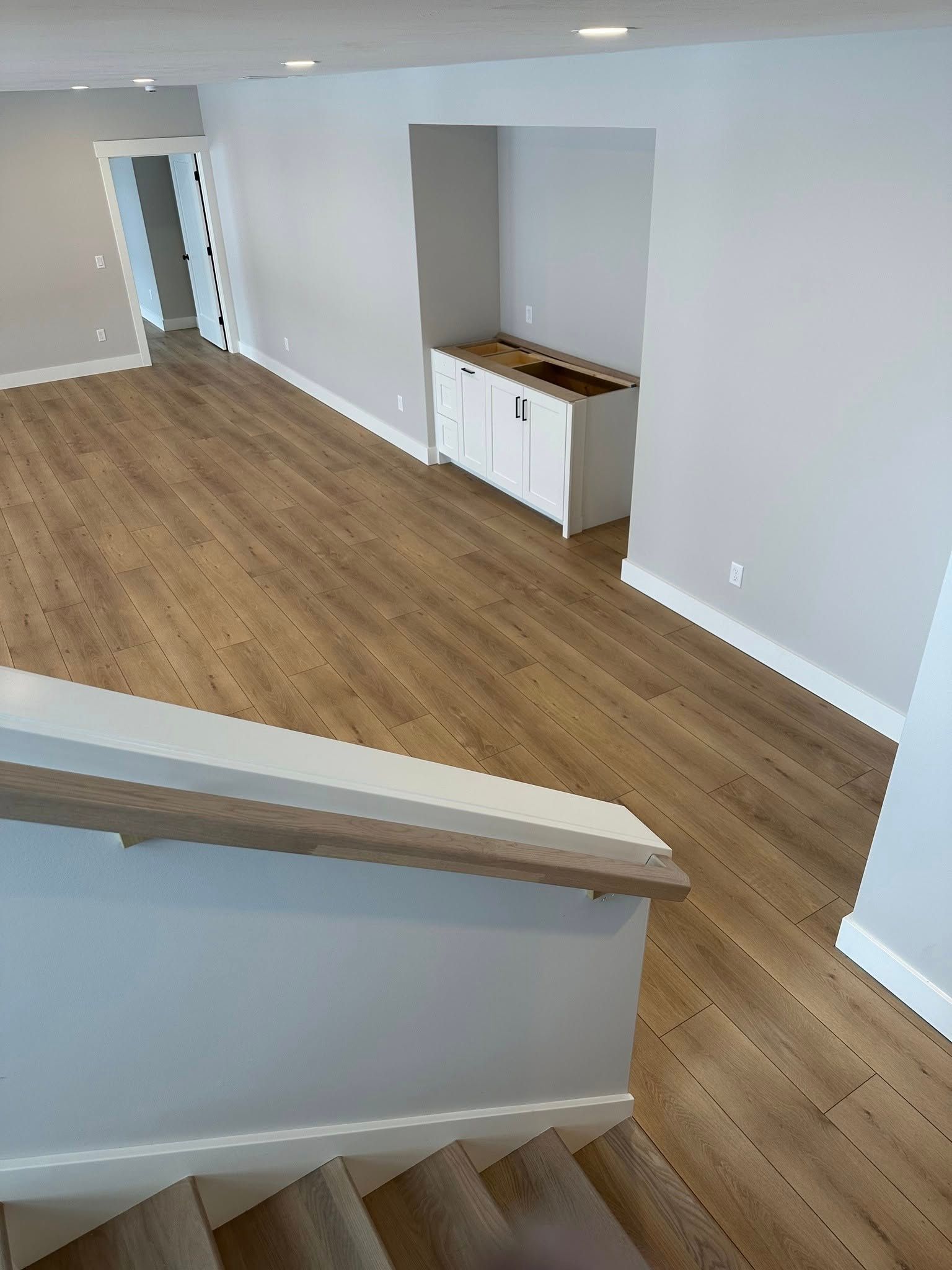 A living room with hardwood floors and stairs leading up to it.
