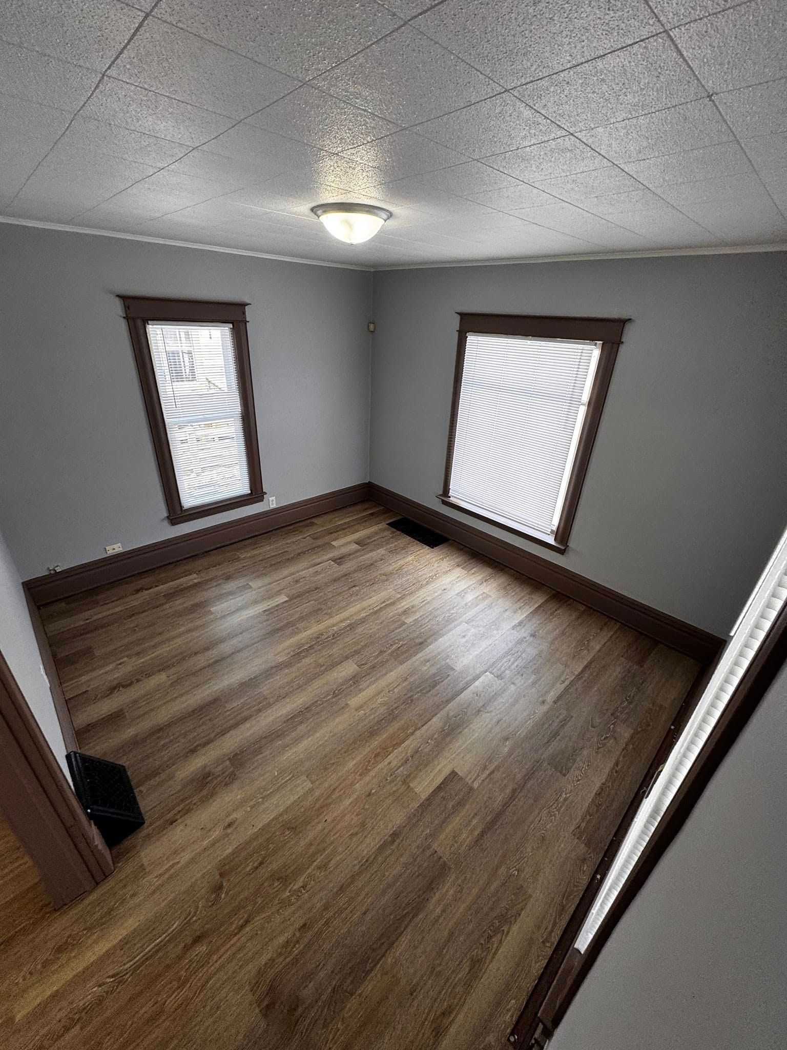 An empty room with hardwood floors and two windows.