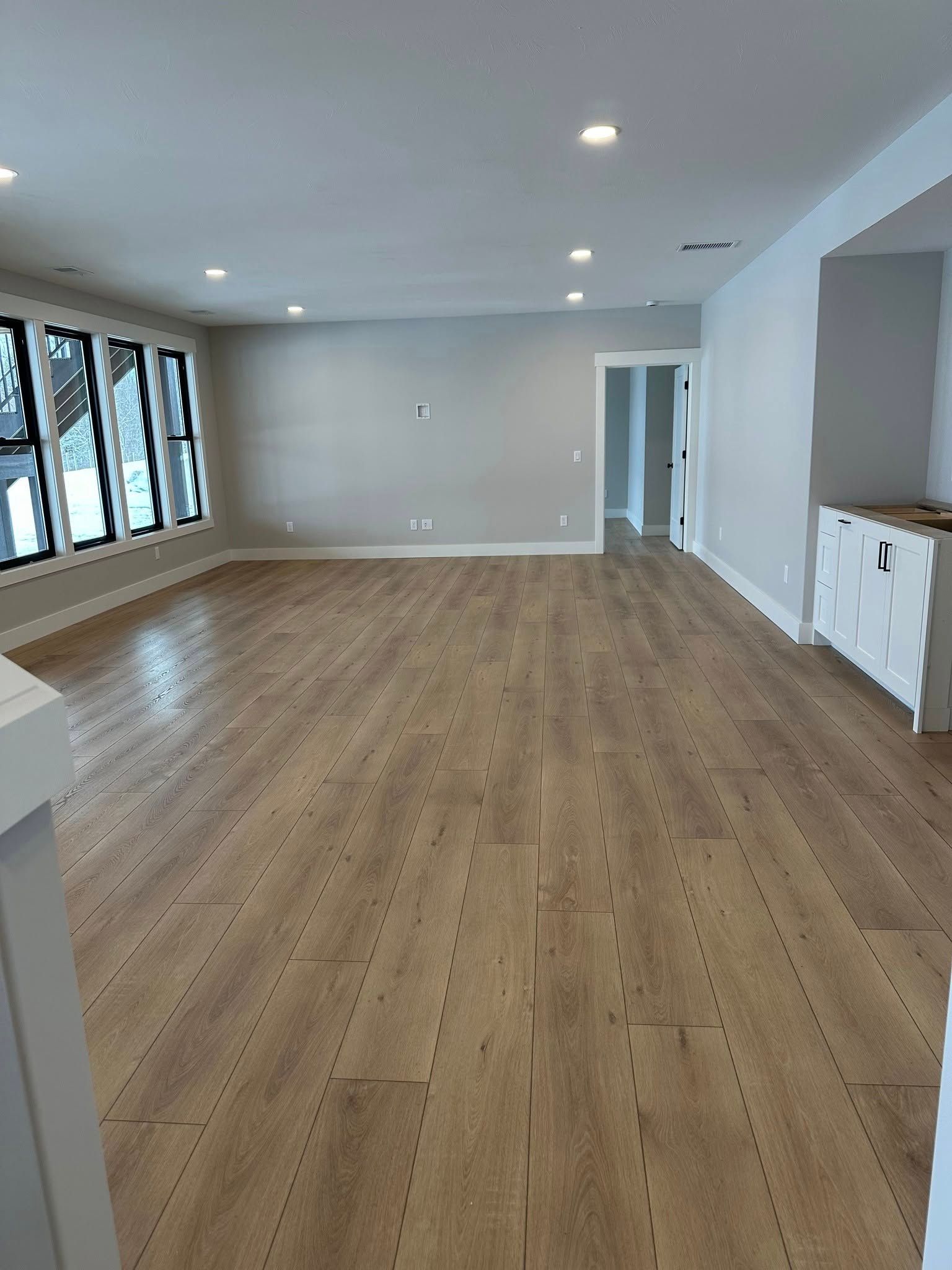 A large empty room with hardwood floors and a lot of windows.