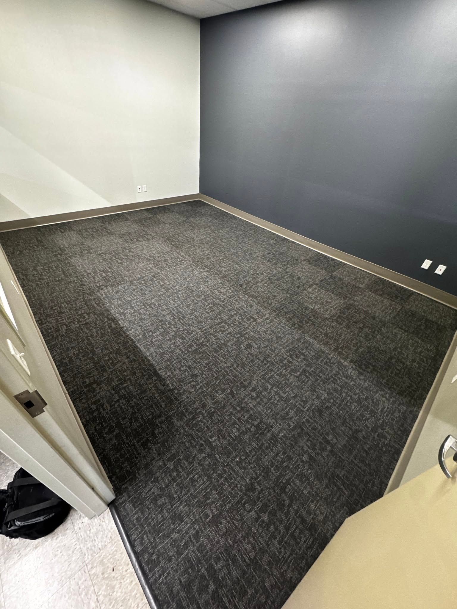 A room with a black carpet and a black wall.