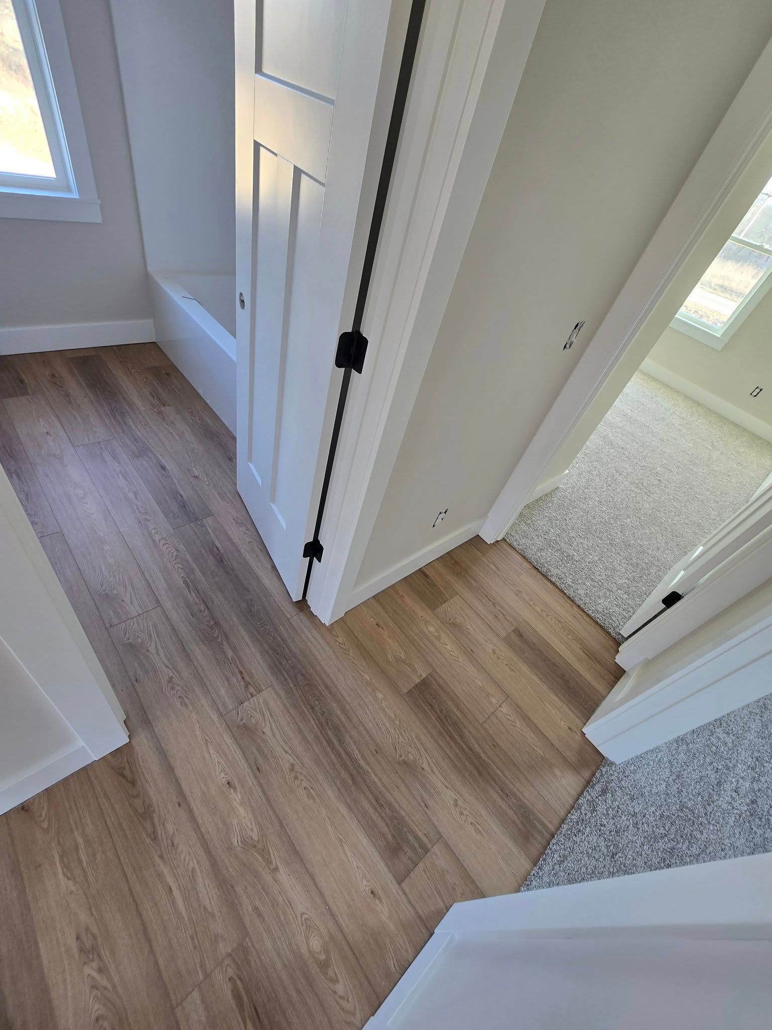 A hallway with hardwood floors and white walls in a house.