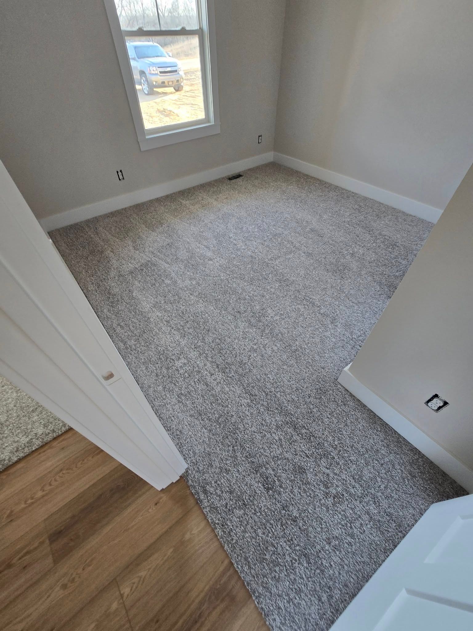 A bedroom with a carpeted floor and a window.