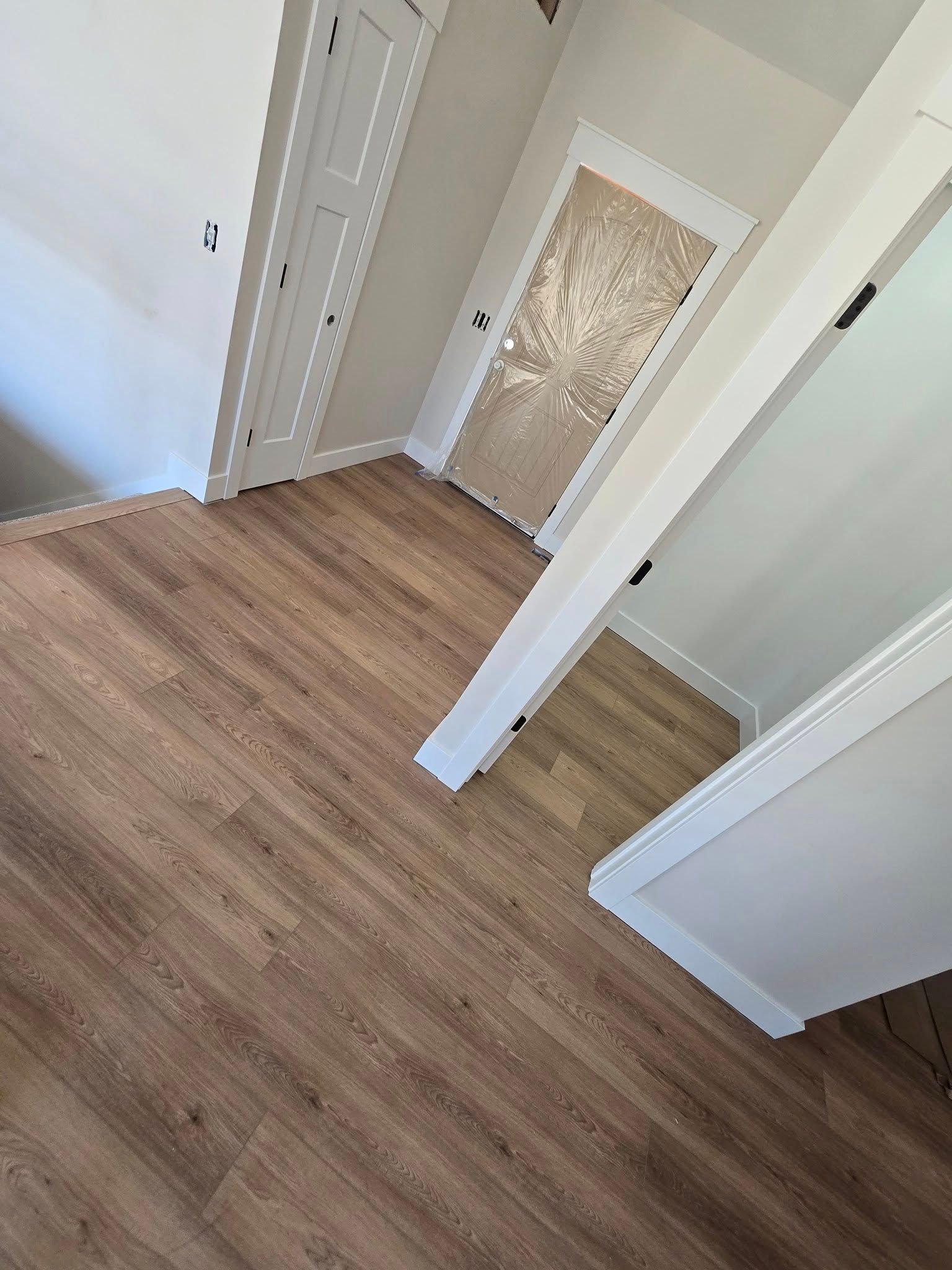 A hallway with hardwood floors and white walls.