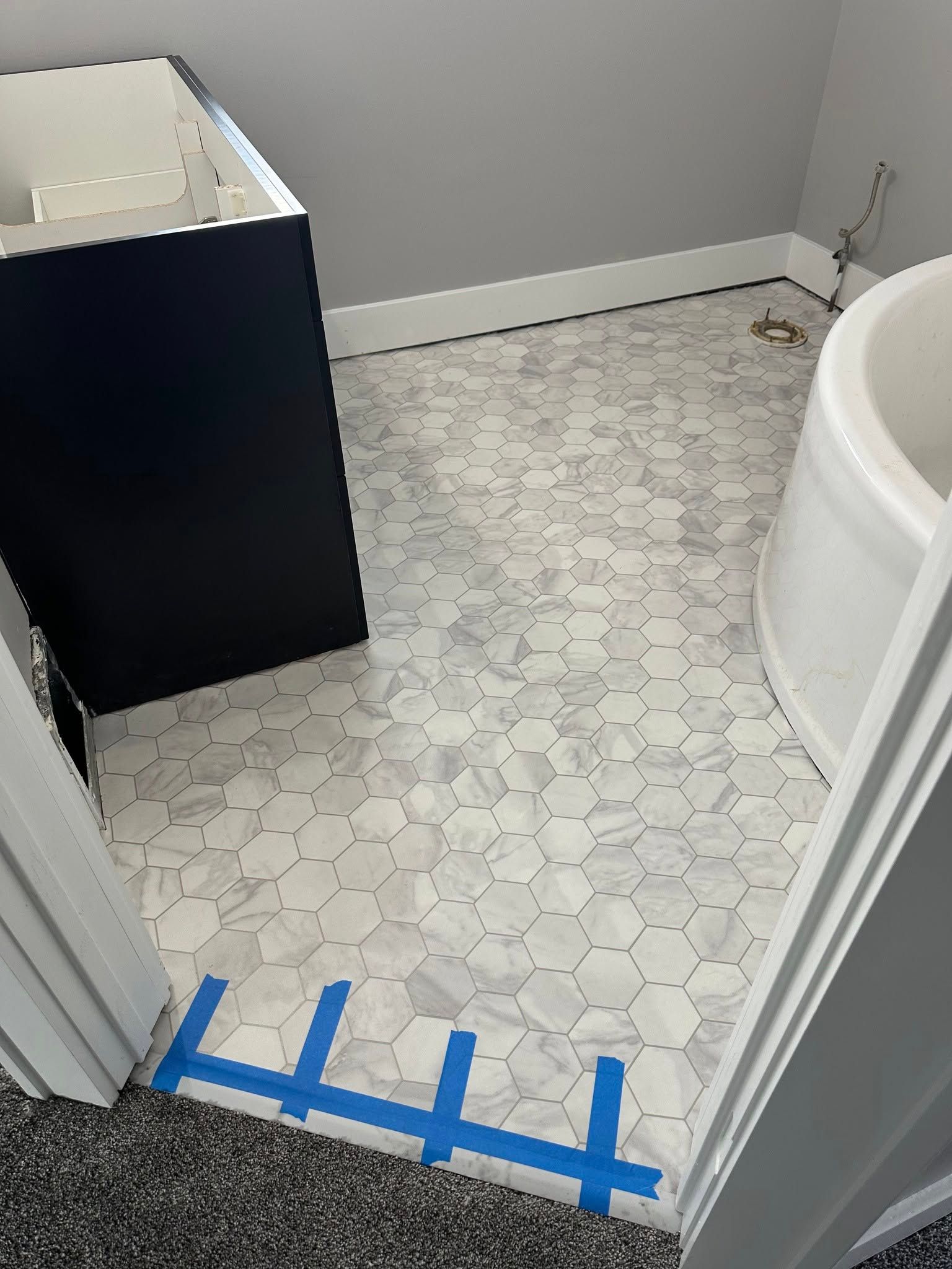 A bathroom with a tub , sink , and tile floor.