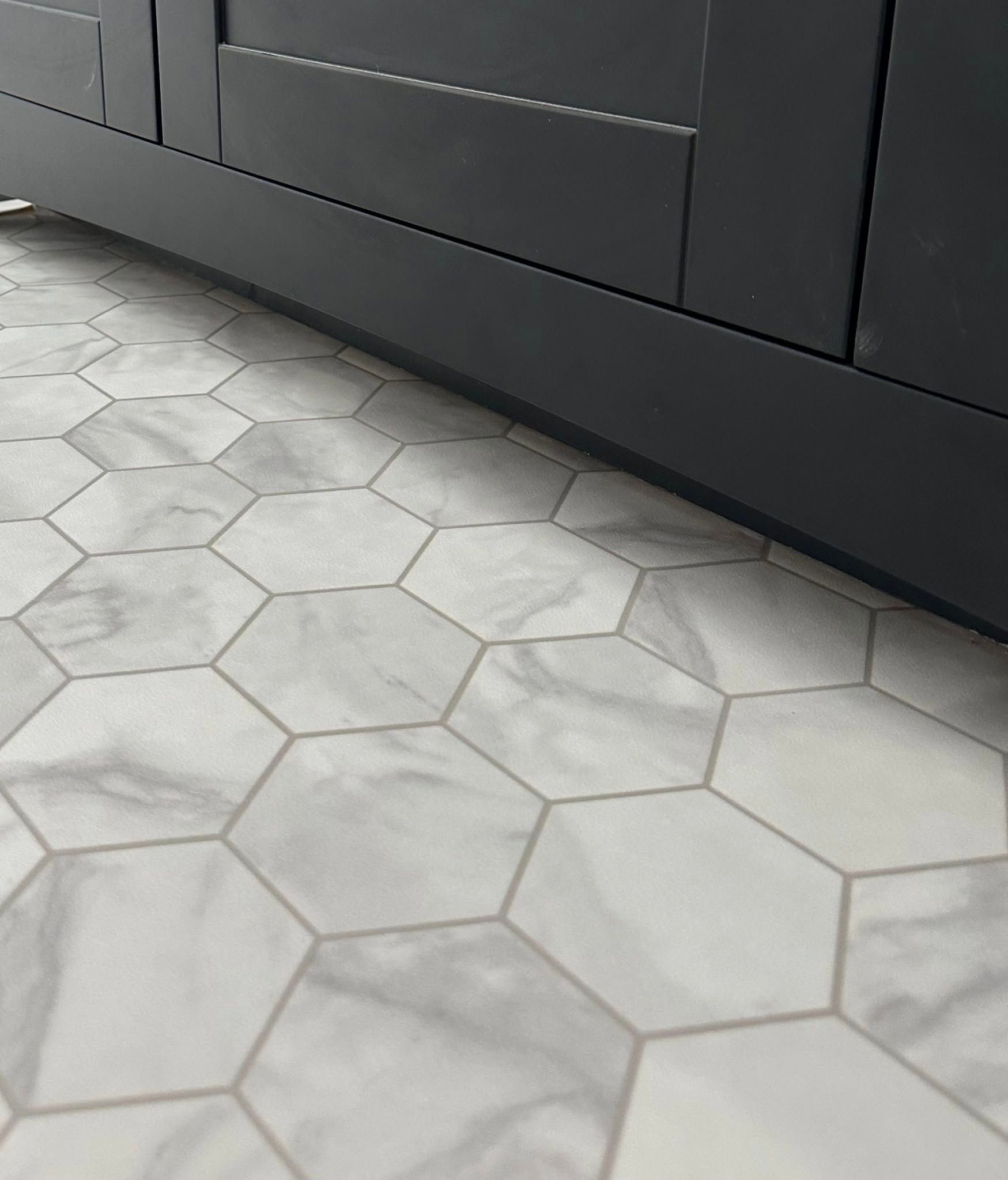 A close up of a hexagon tile floor next to a cabinet.