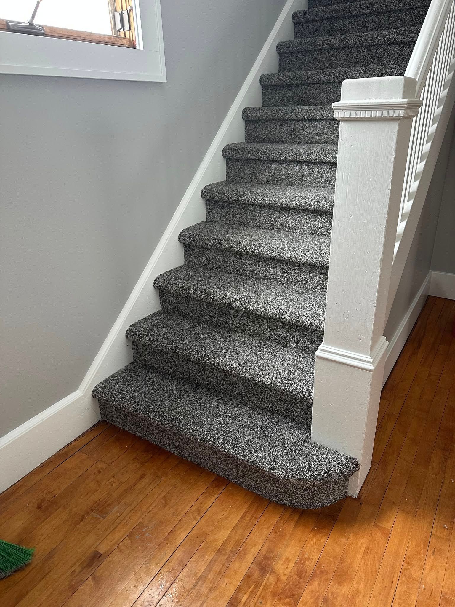 A staircase with a carpeted staircase and a wooden floor.