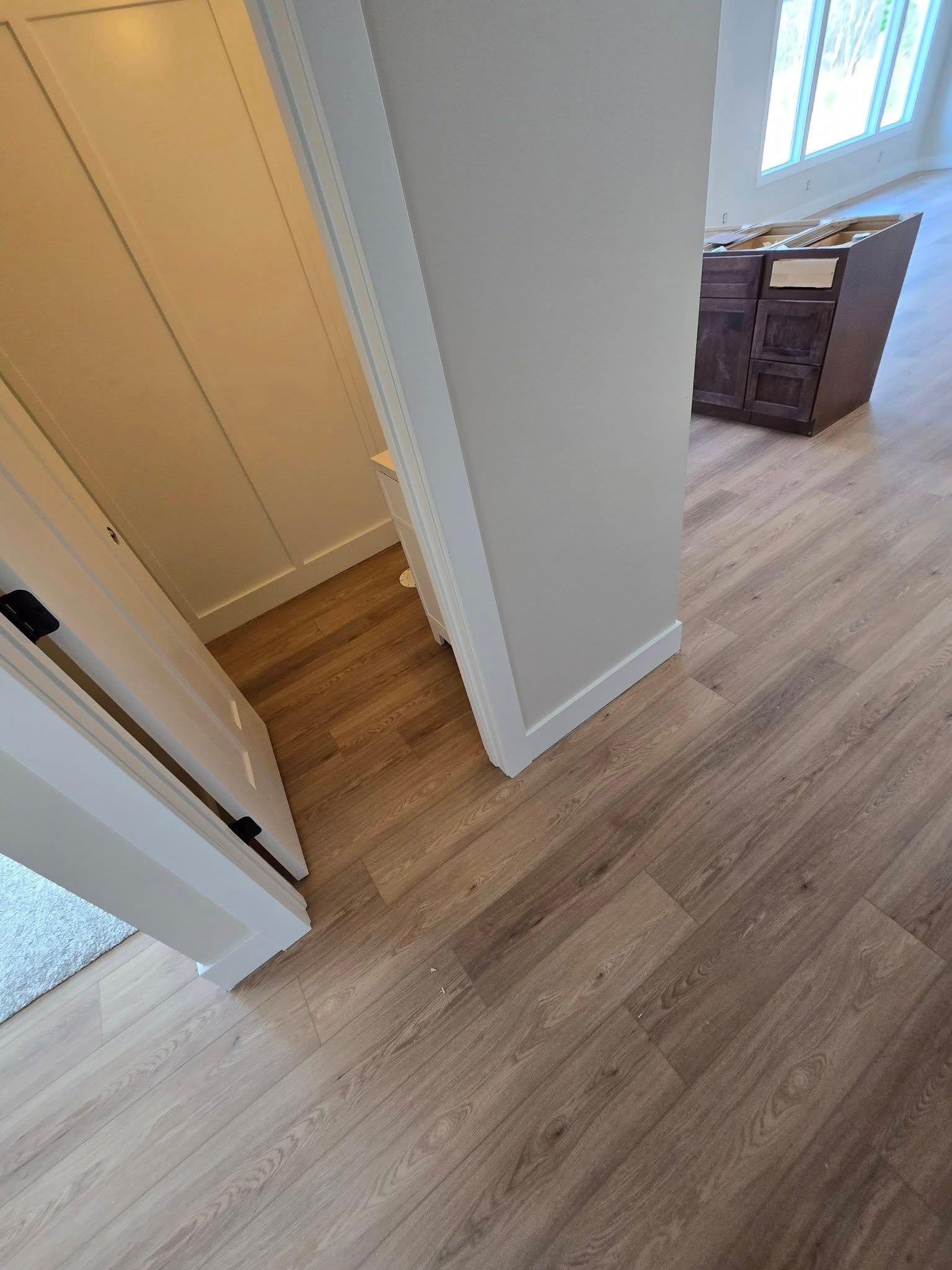 A hallway with hardwood floors and white walls in a house.