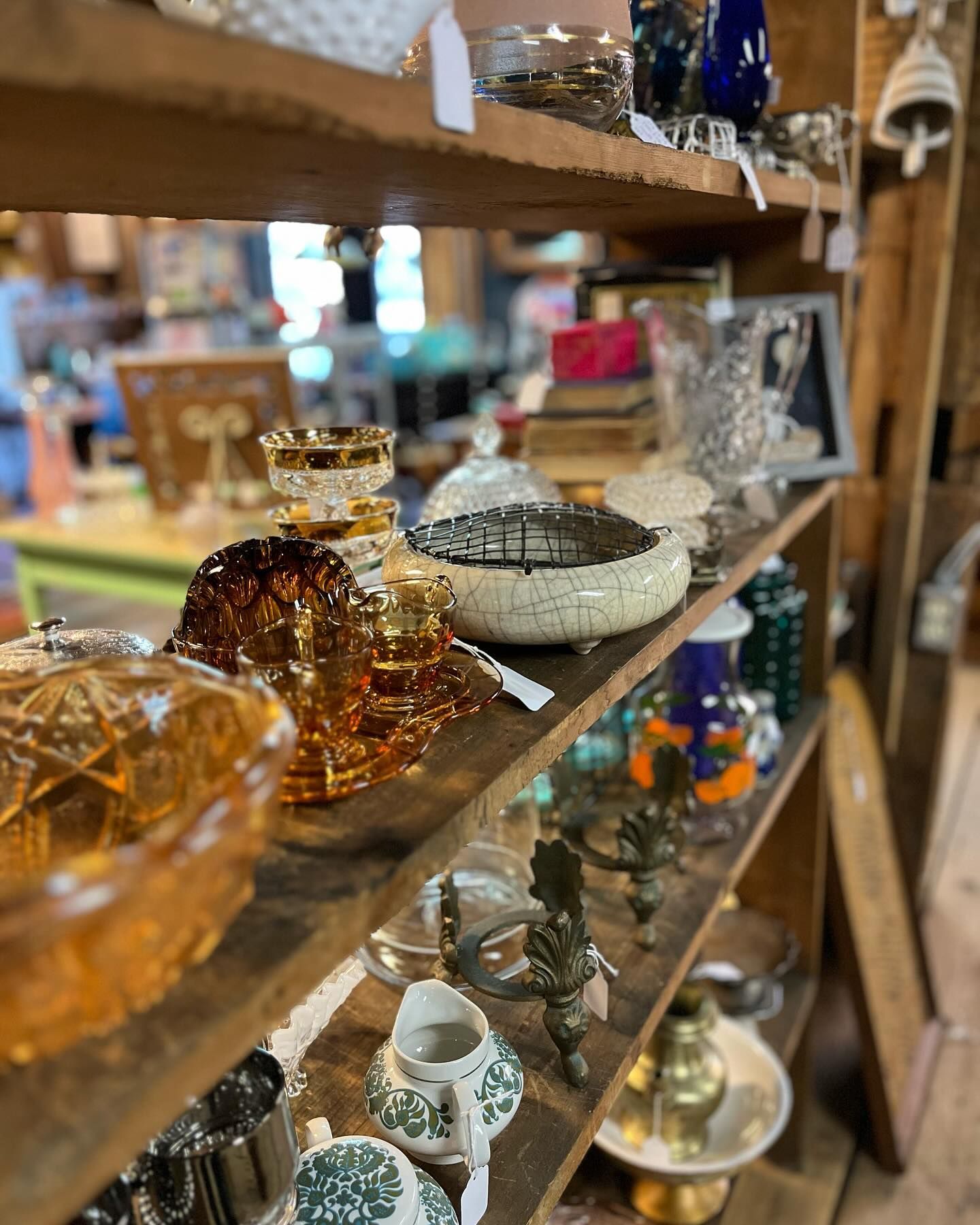 Glass decor and small figurines displayed on wooden shelves in a shop