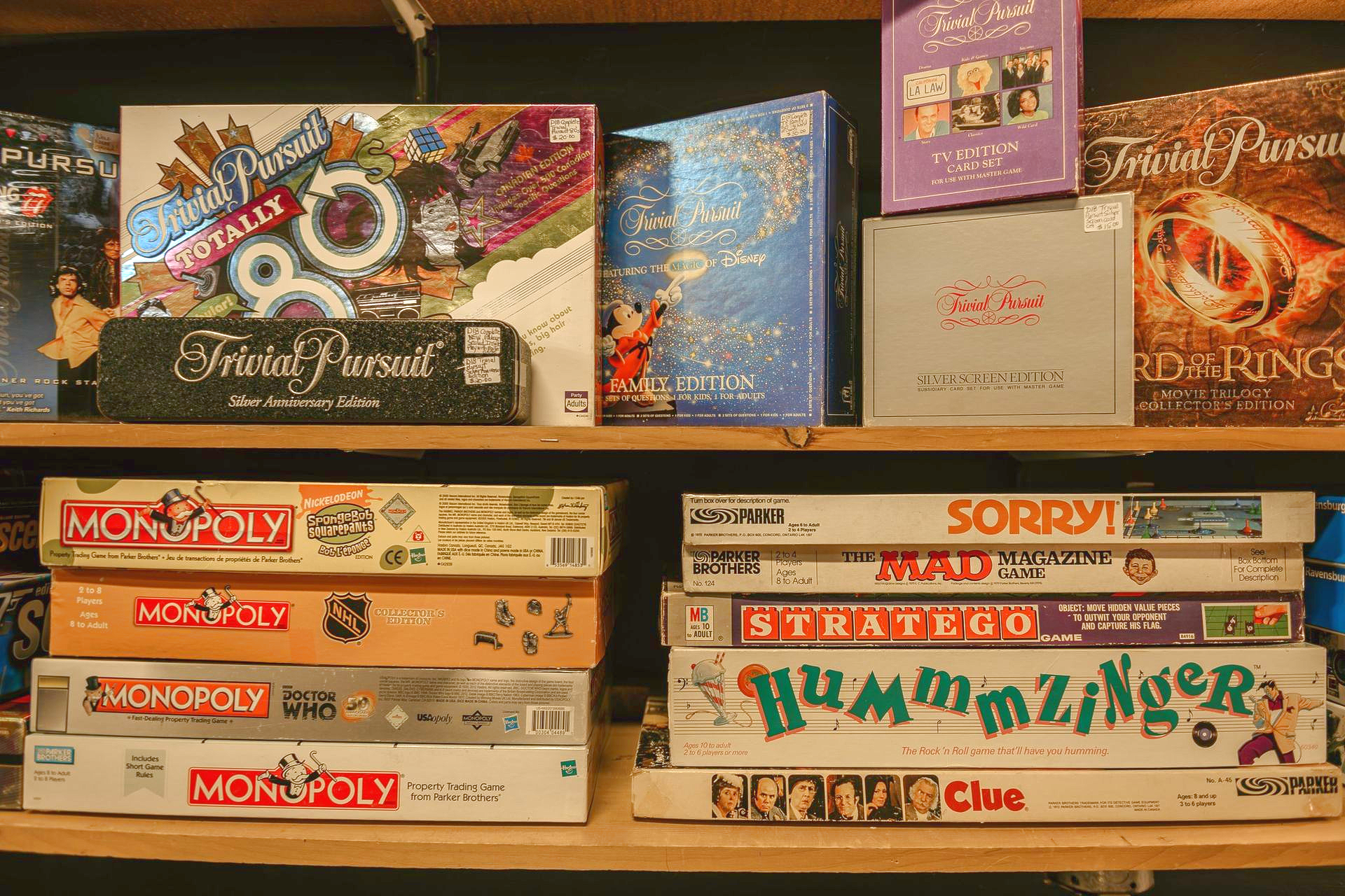 Stacked board games on shelves, including Monopoly, Risk, Clue, and A Game of Thrones.