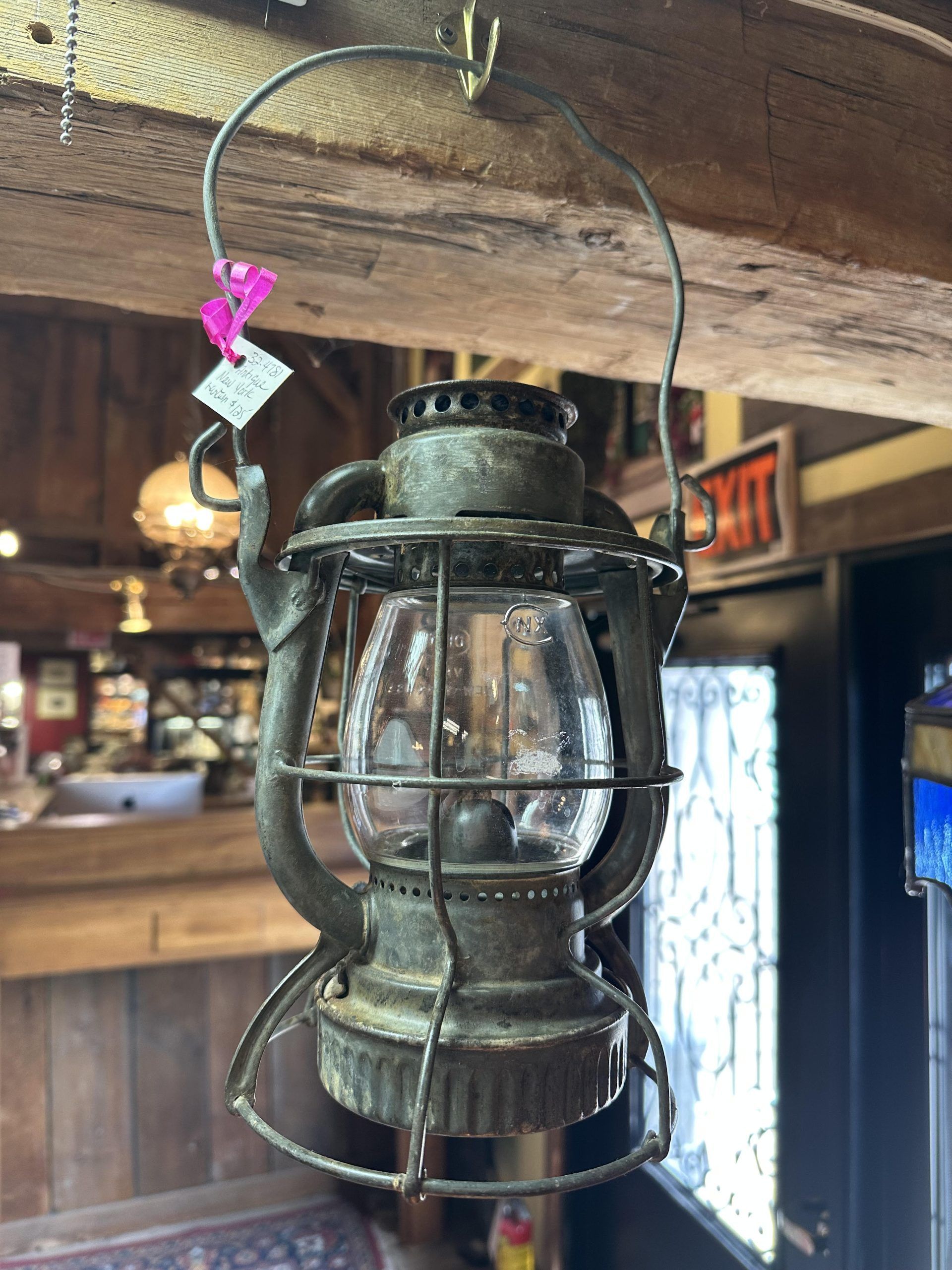 Old black metal lantern hanging from a rustic wooden beam indoors