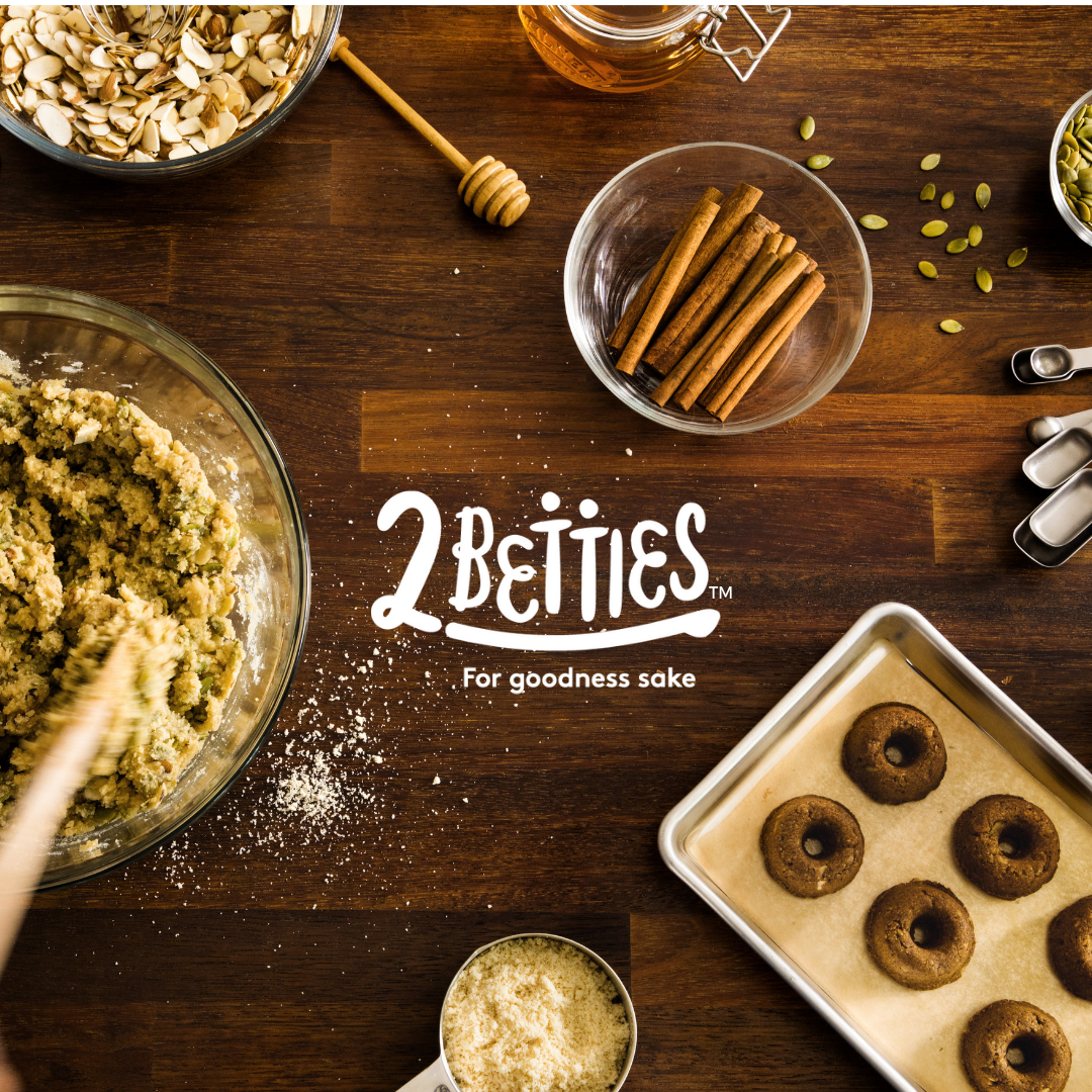 A wooden table topped with bowls of food and the words 2 betties