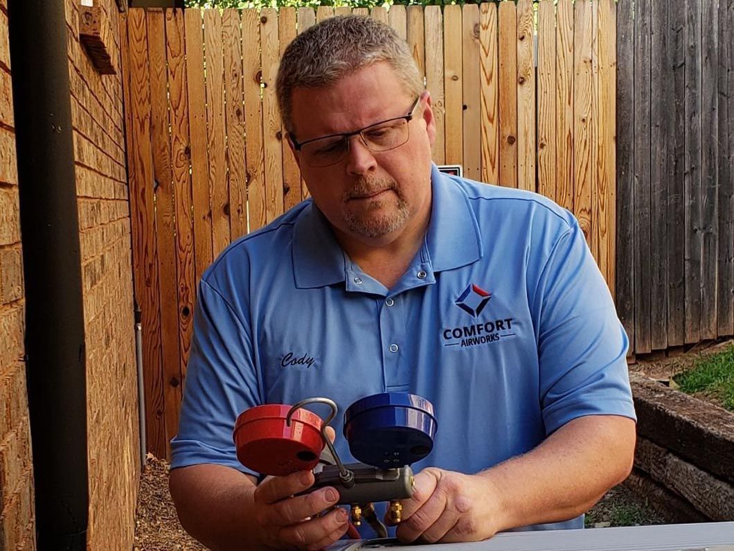 Cody in a blue shirt is holding two valves in his hands.