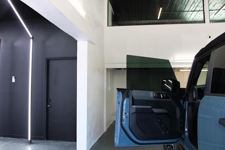 A Ford Bronco with tinted windows and an open door in a modern building.