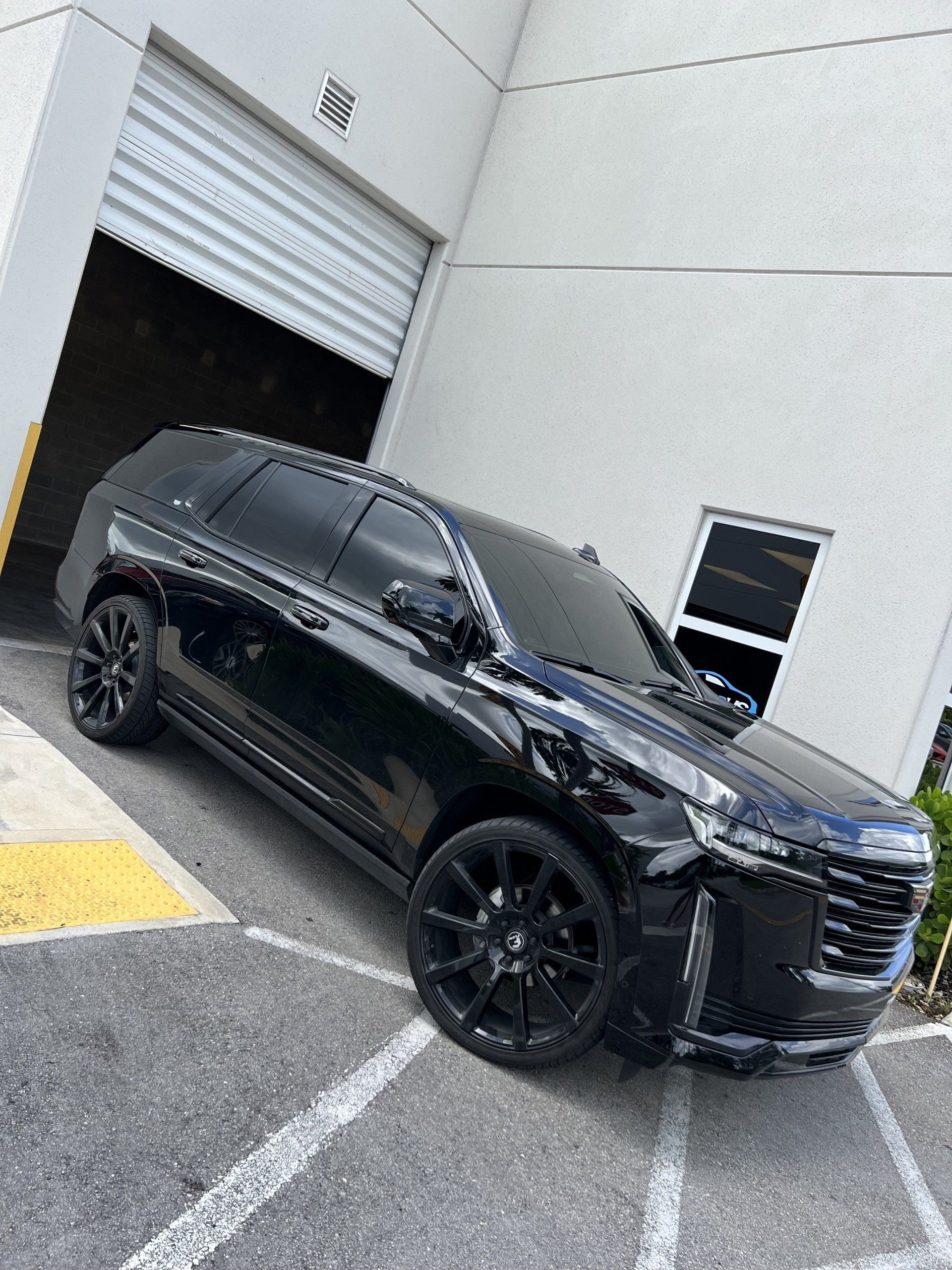 Black SUV parked outside a building with a garage door.