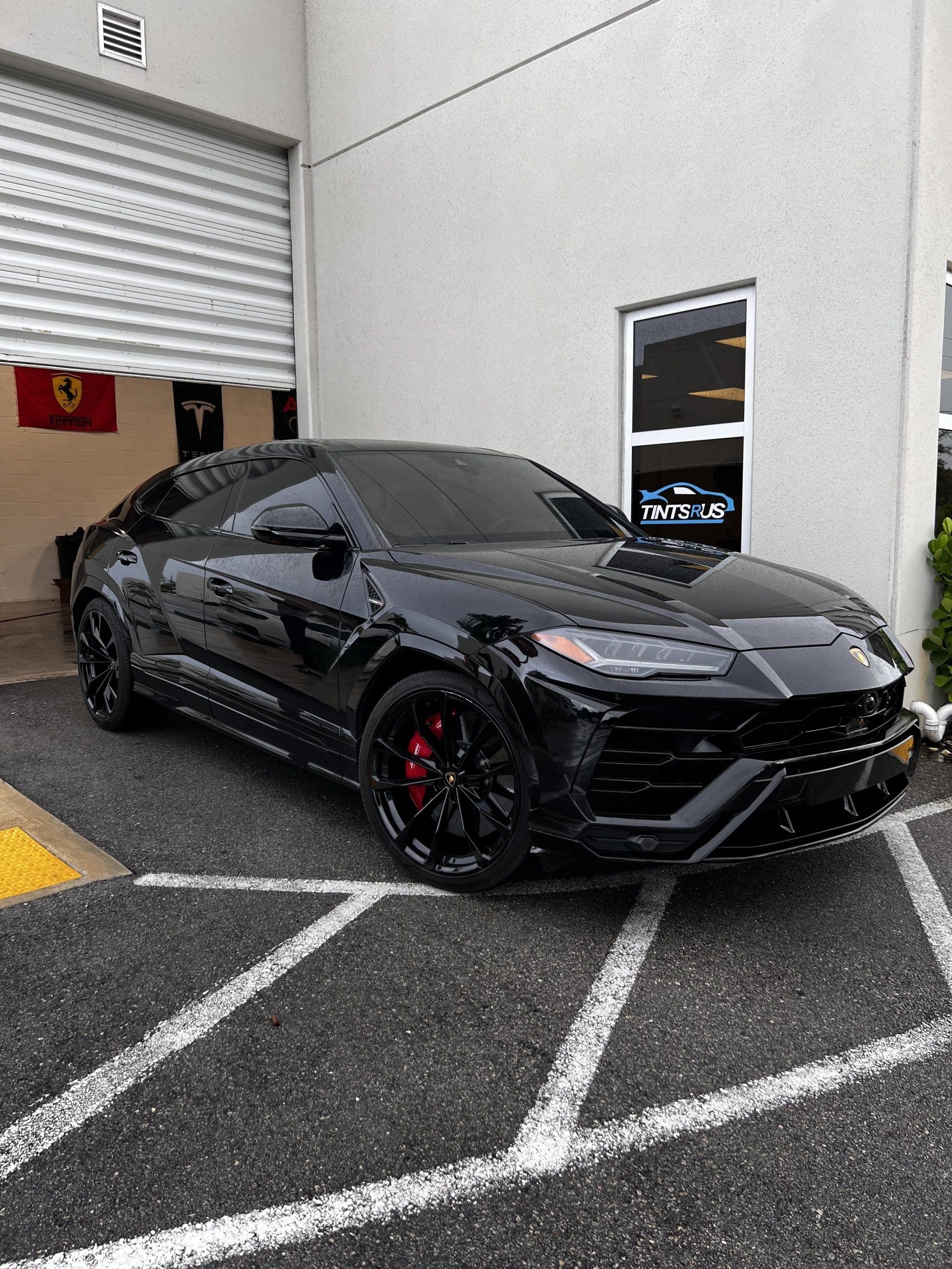 Black Lamborghini Urus SUV parked outside a building. Red brake calipers visible.