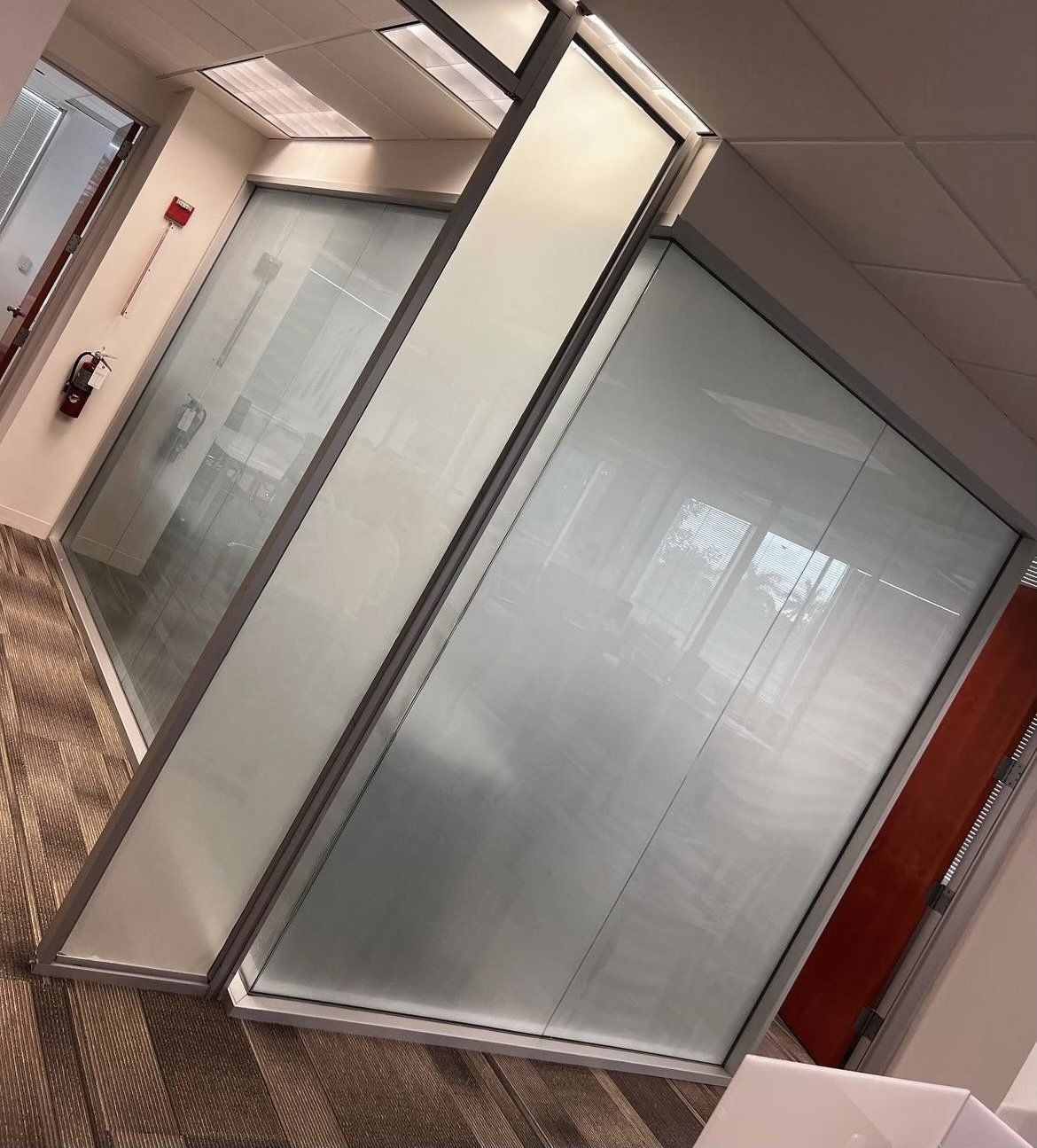 Office hallway with frosted glass walls and a fire extinguisher.