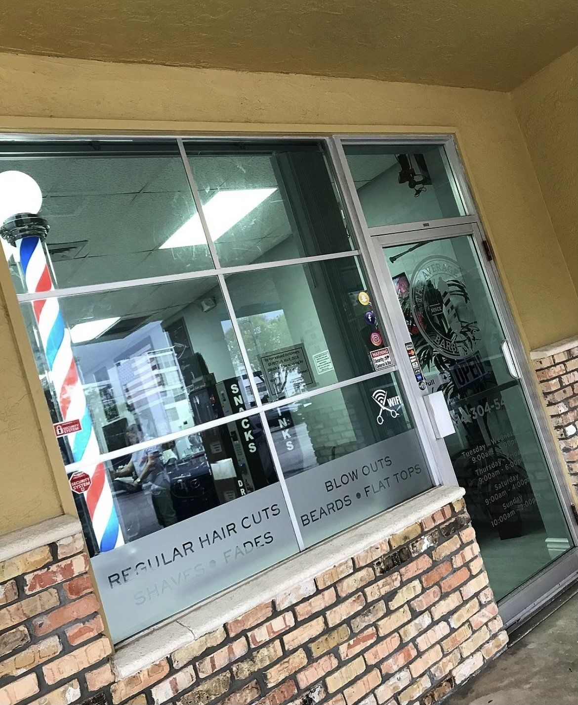 Barber shop storefront with a striped pole, window text, and a brick facade.