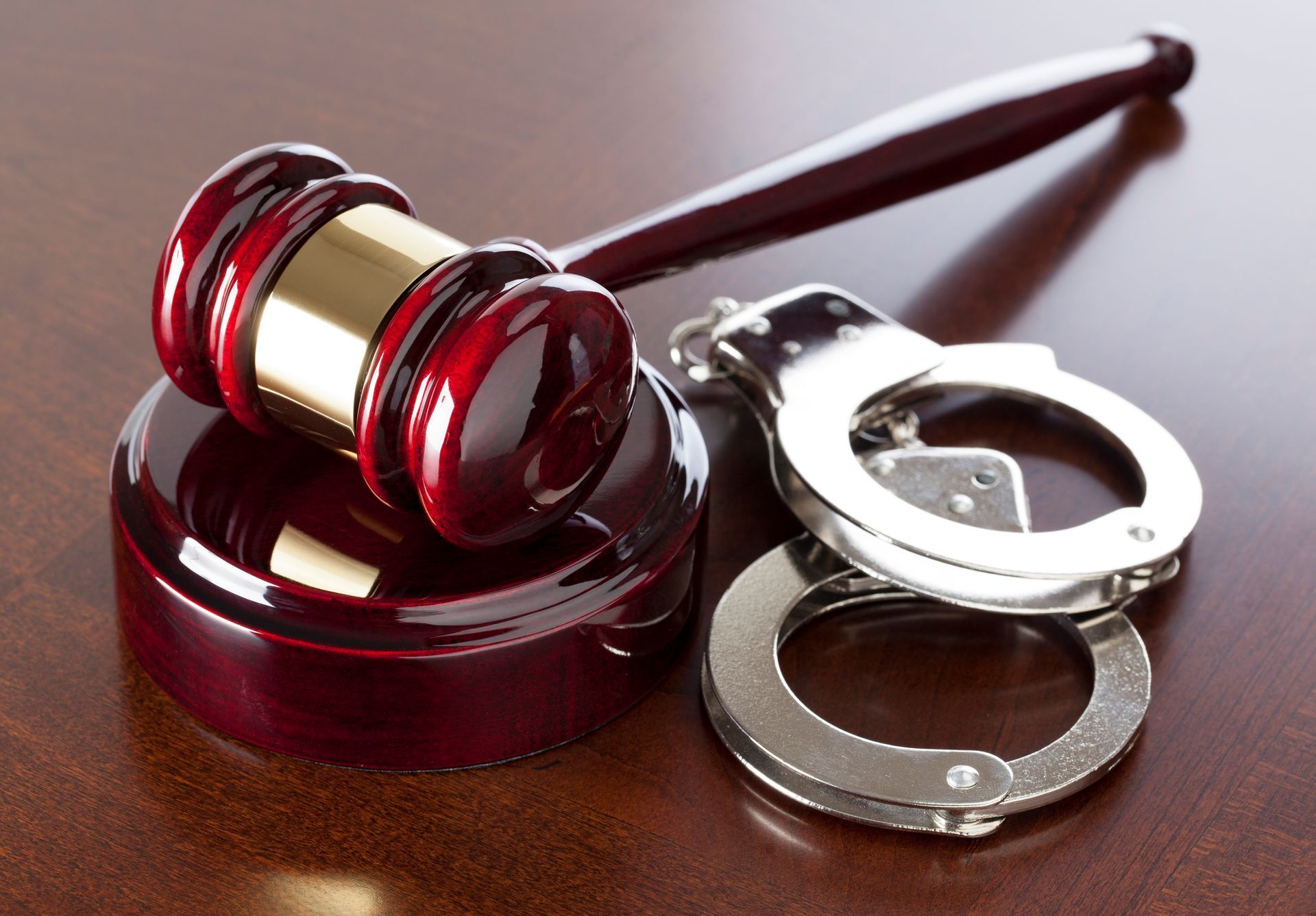 A gavel and handcuffs resting on a wooden table, symbolizing criminal justice