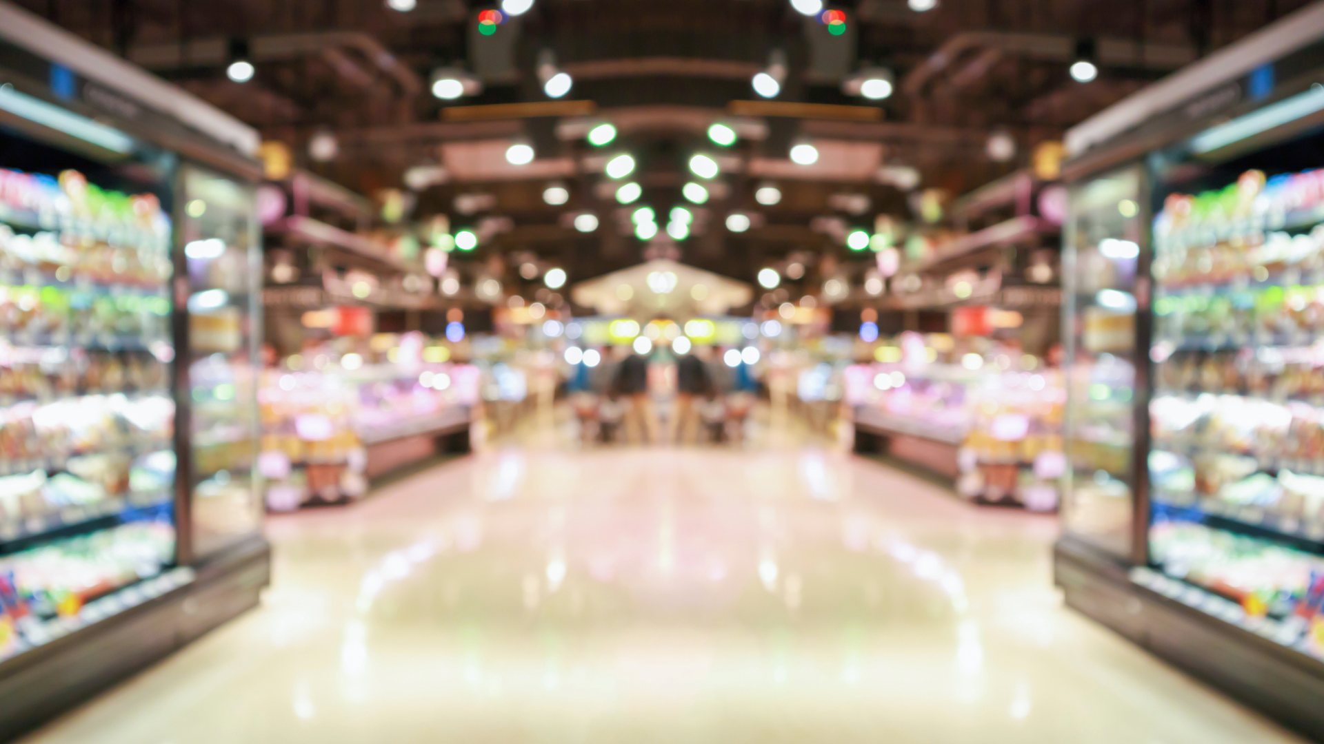 A blurred image of a grocery store with lots of shelves and refrigerators.