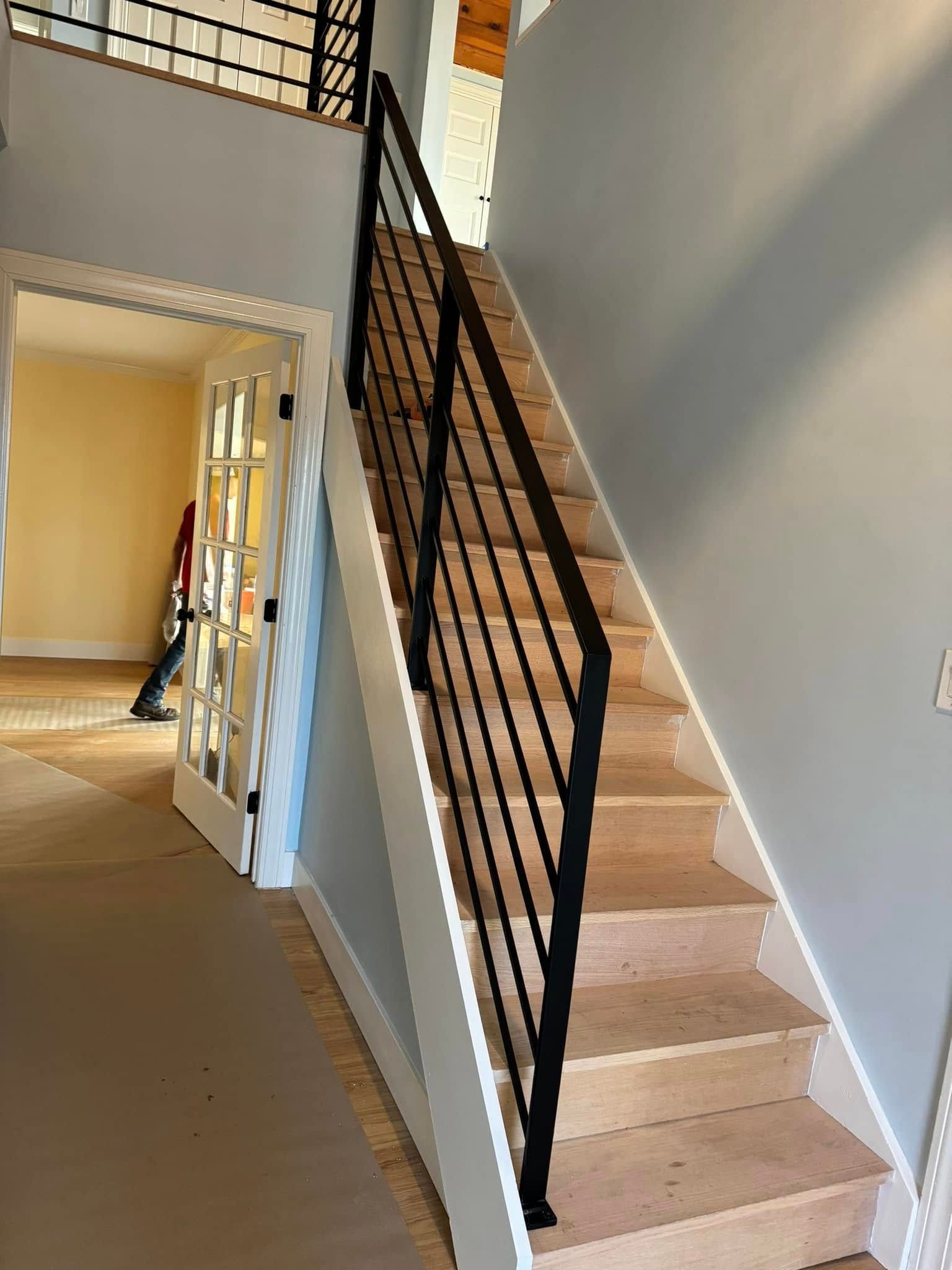 A wooden staircase with a black railing in a house.