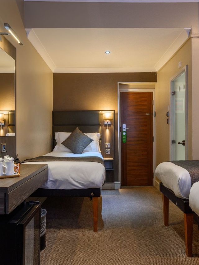 una habitación de hotel con una cama individual y dos camas individuales