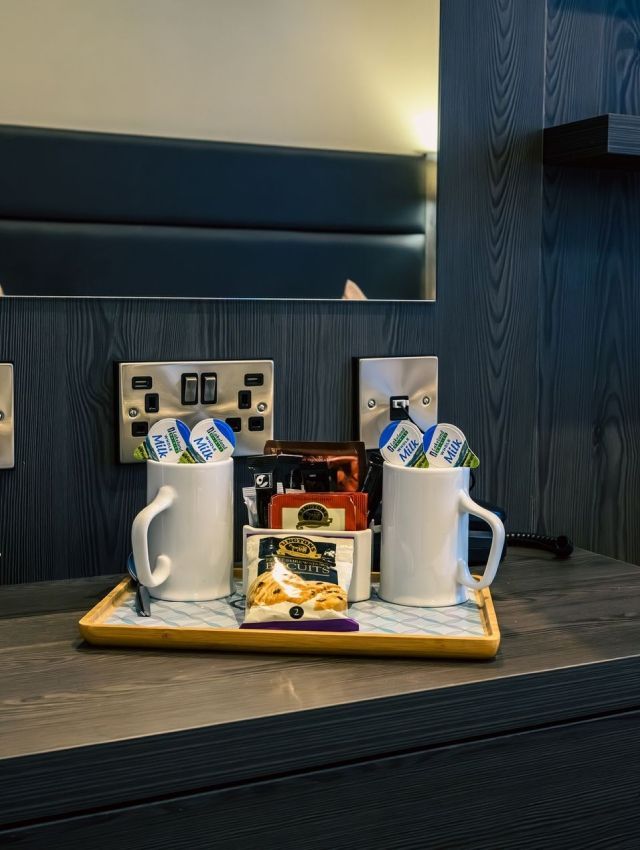 una habitación de hotel con una bandeja de tazas de café y condimentos.