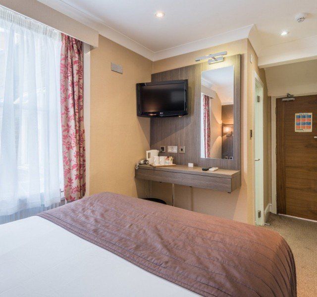 una camera d'albergo con un letto, un televisore e uno specchio