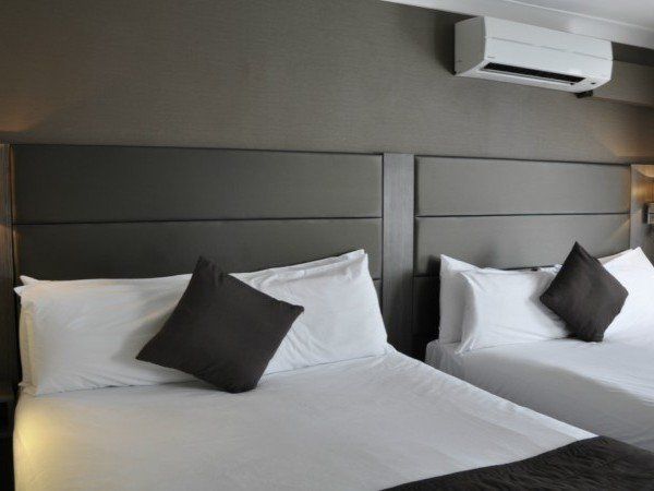 due letti in una camera d'albergo con lenzuola e cuscini bianchi