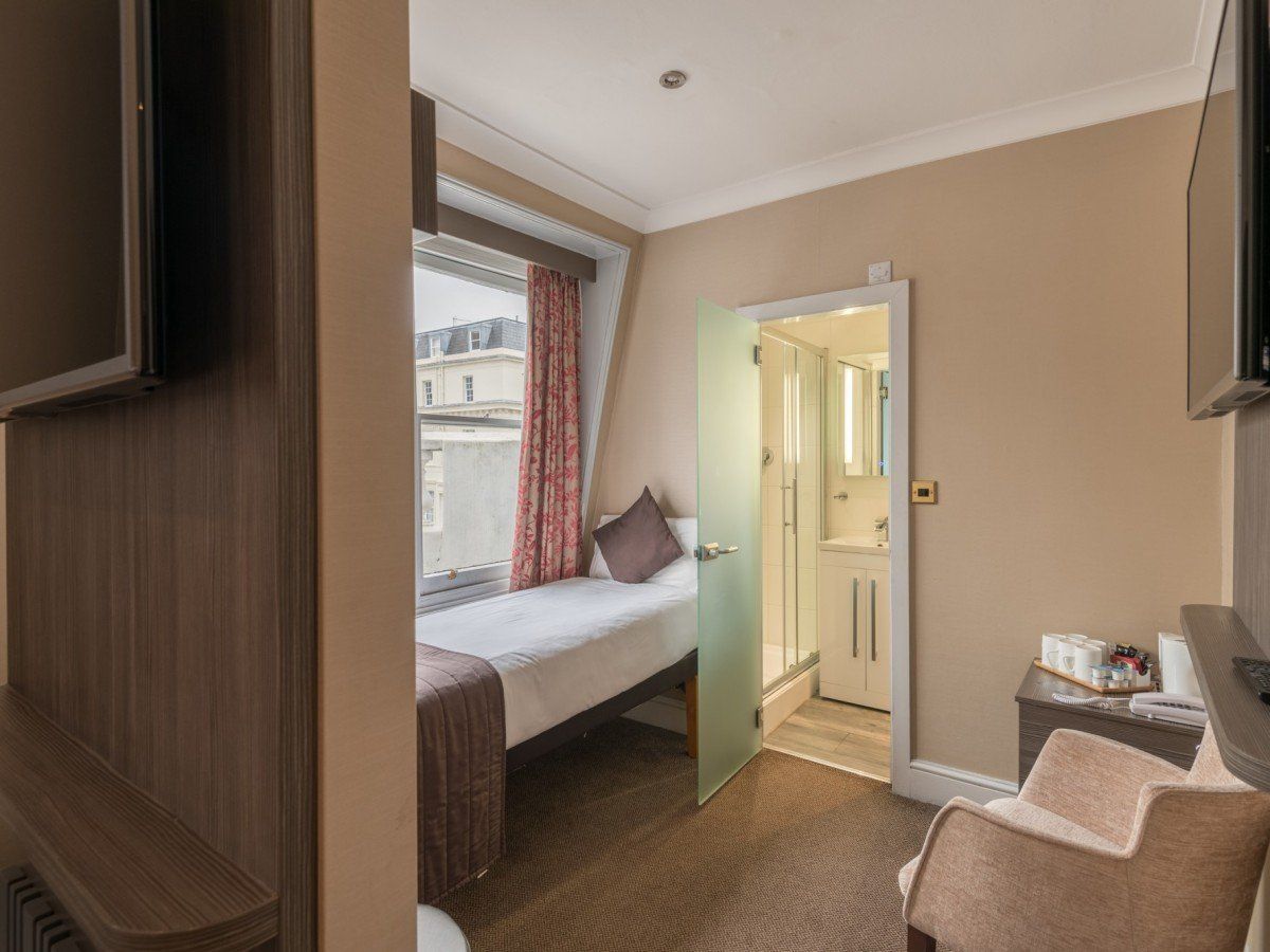 una camera d'albergo con un letto singolo, una sedia e un televisore.