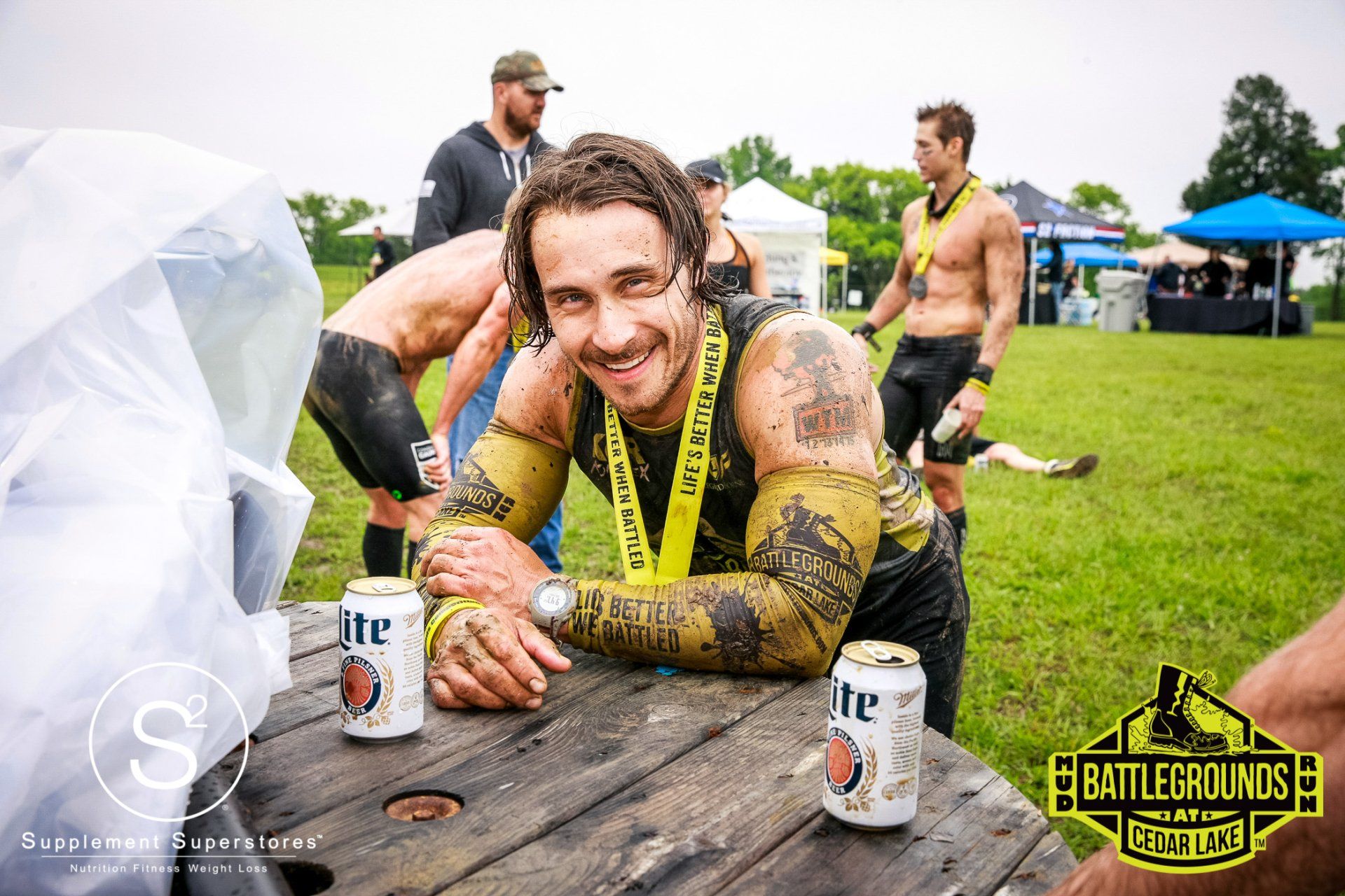 A man is sitting at a picnic table with two cans of lite beer.