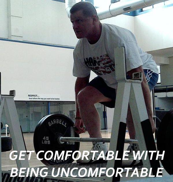 A man lifting a barbell with the words get comfortable with being uncomfortable below him