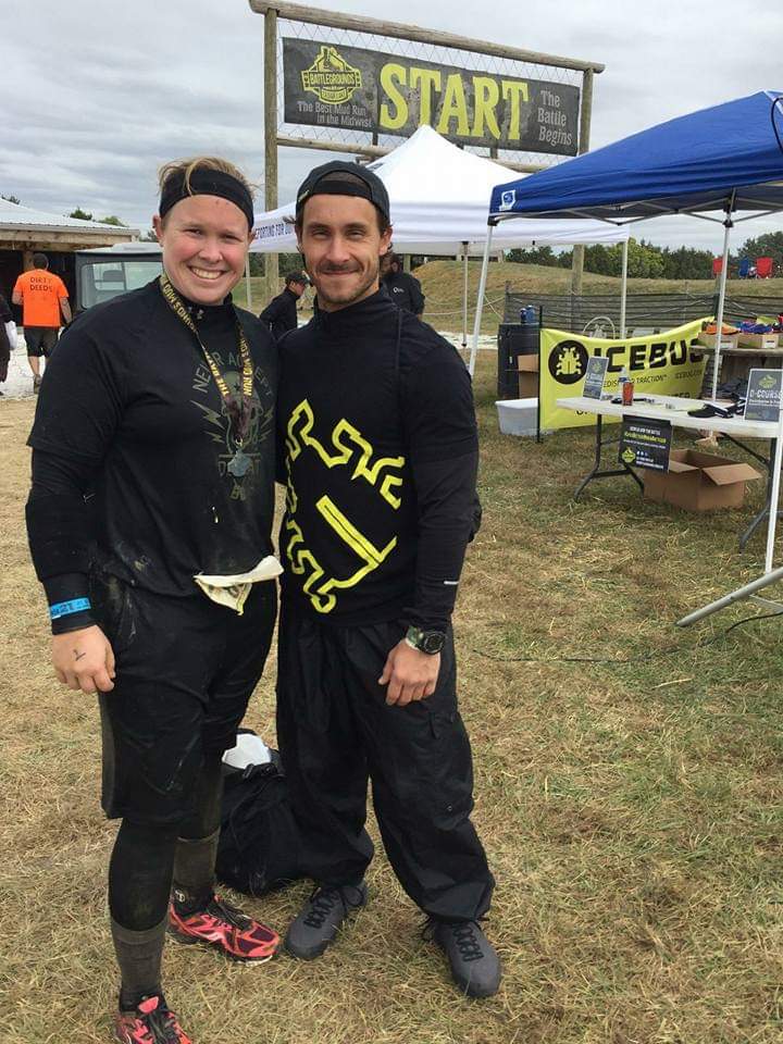 A man and a woman are posing for a picture in front of a sign that says start