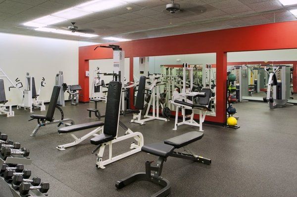 A gym with a lot of equipment and a red wall